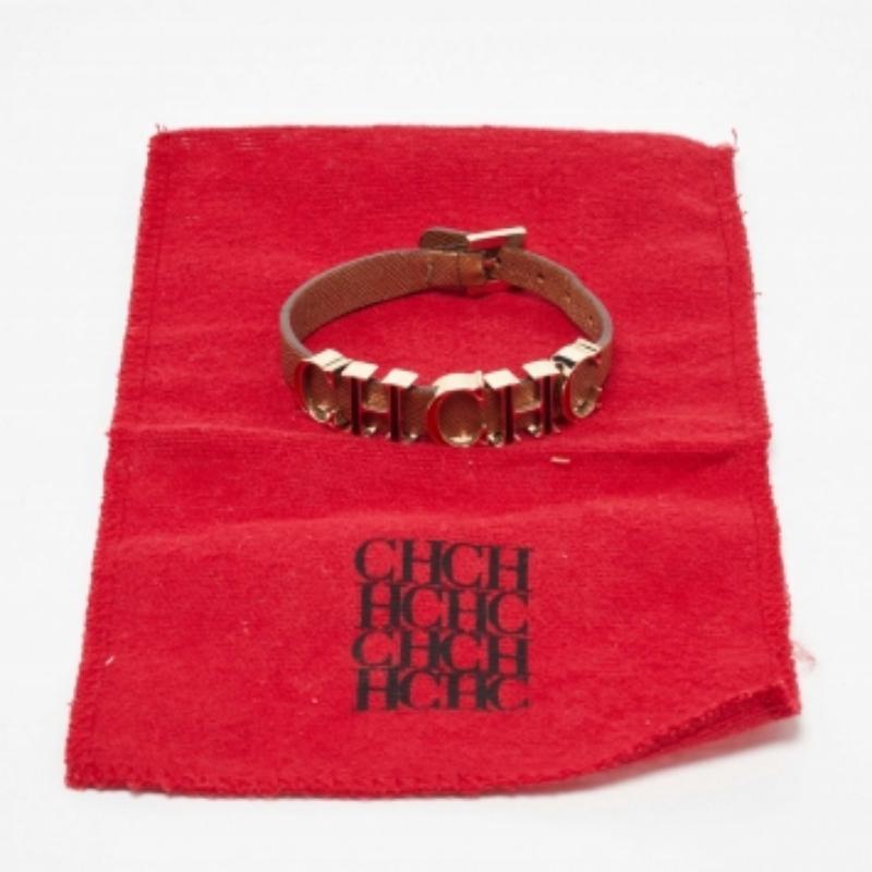 Das Armband CH Carolina Herrera ist ein elegantes Accessoire. Sie verfügt über ein braunes Lederband mit einem goldfarbenen, emaillierten CH-Logo als Herzstück. Dieses stilvolle Armband vereint Luxus und Raffinesse und ist eine vielseitige Ergänzung