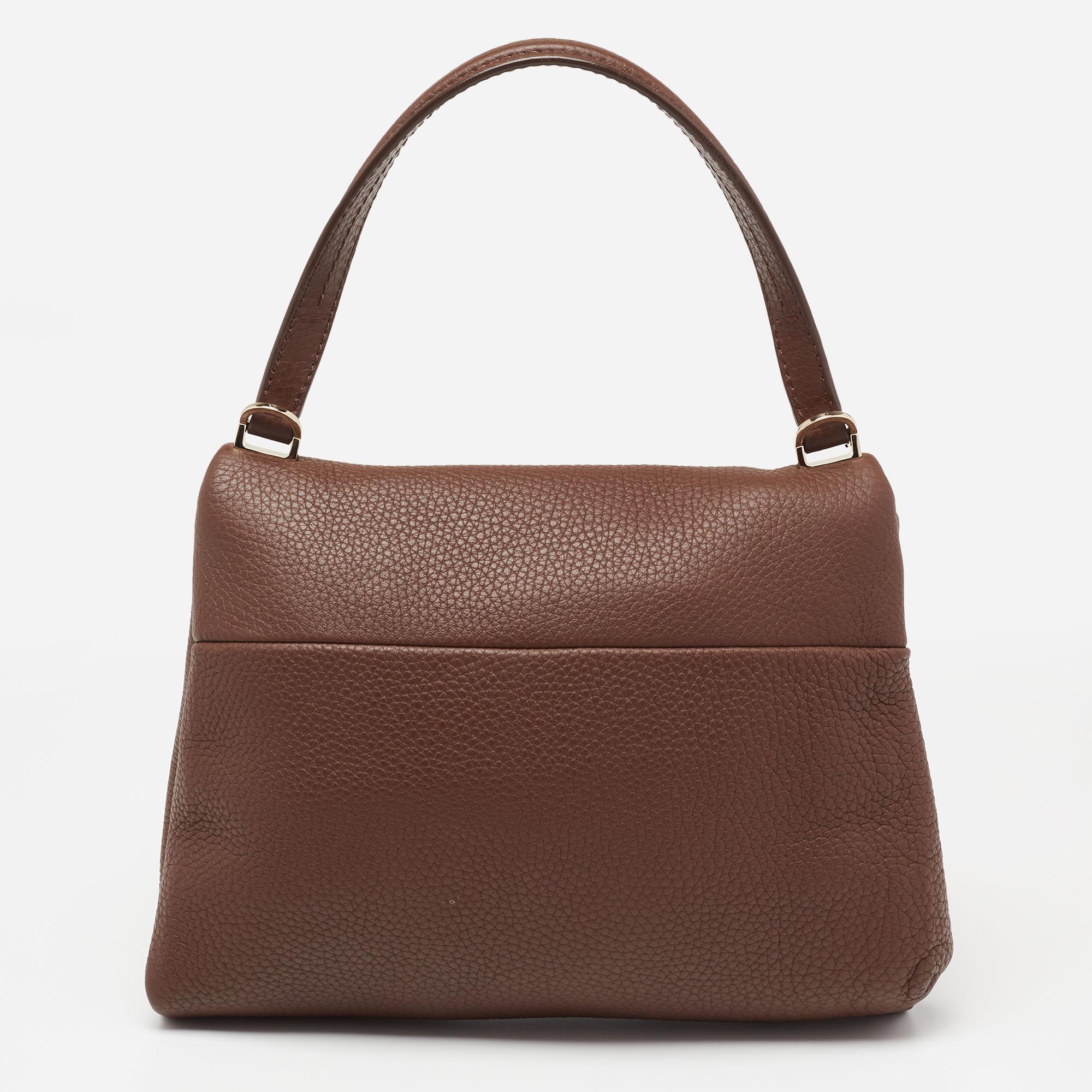 This dark brown bag comes from CH Carolina Herrera. Crafted from textured leather, it has a lined interior that ensures to house your everyday essentials effortlessly. The top handle bag is complete with a metal trim on the flap.

Includes: Original