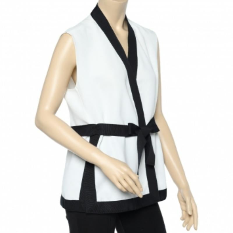 ¡Qué elegantemente clásico es este encogimiento de hombros blanco con ribetes negros! Diseñado por CH Carolina Herrera, el encogimiento de hombros sin mangas está confeccionado en tela y ostenta un detalle de cinturón que se suma a la estilizada