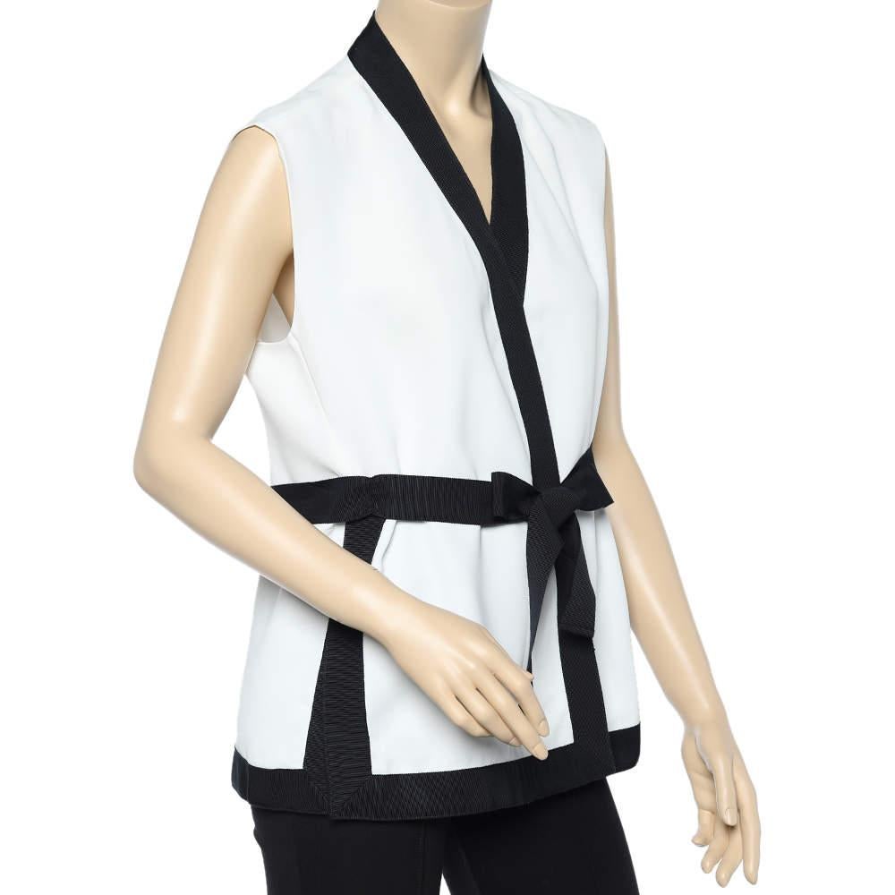 How elegantly classic is this white shrug with black trims! Designed by CH Carolina Herrera, the sleeveless shrug is made using twill fabric and flaunts a belted detail that adds to the overall stylish silhouette. Wear it with black-hued pants or