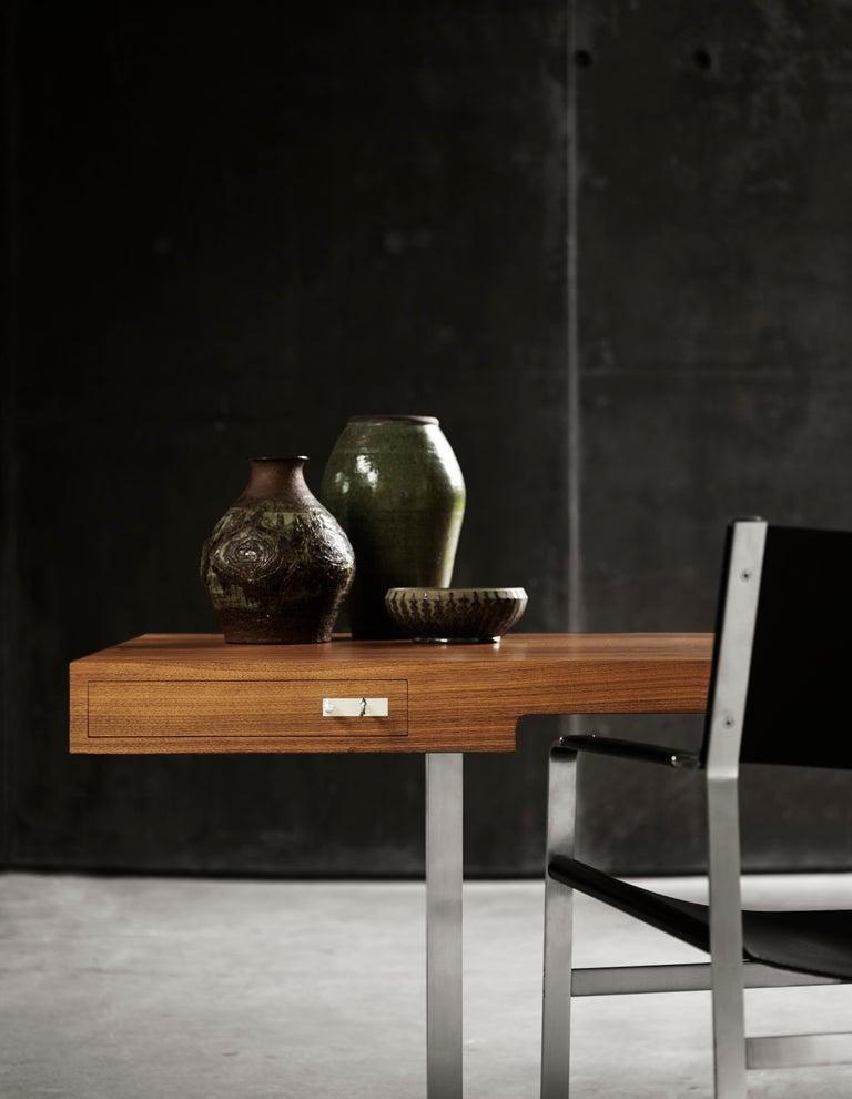 In the CH110 desk, Wegner illustrates another side of his talent for furniture design in the gathering of the tabletop, rails and two slender drawers into one large veneered element, resting upon two slim supporting legs in stainless flat steel. The