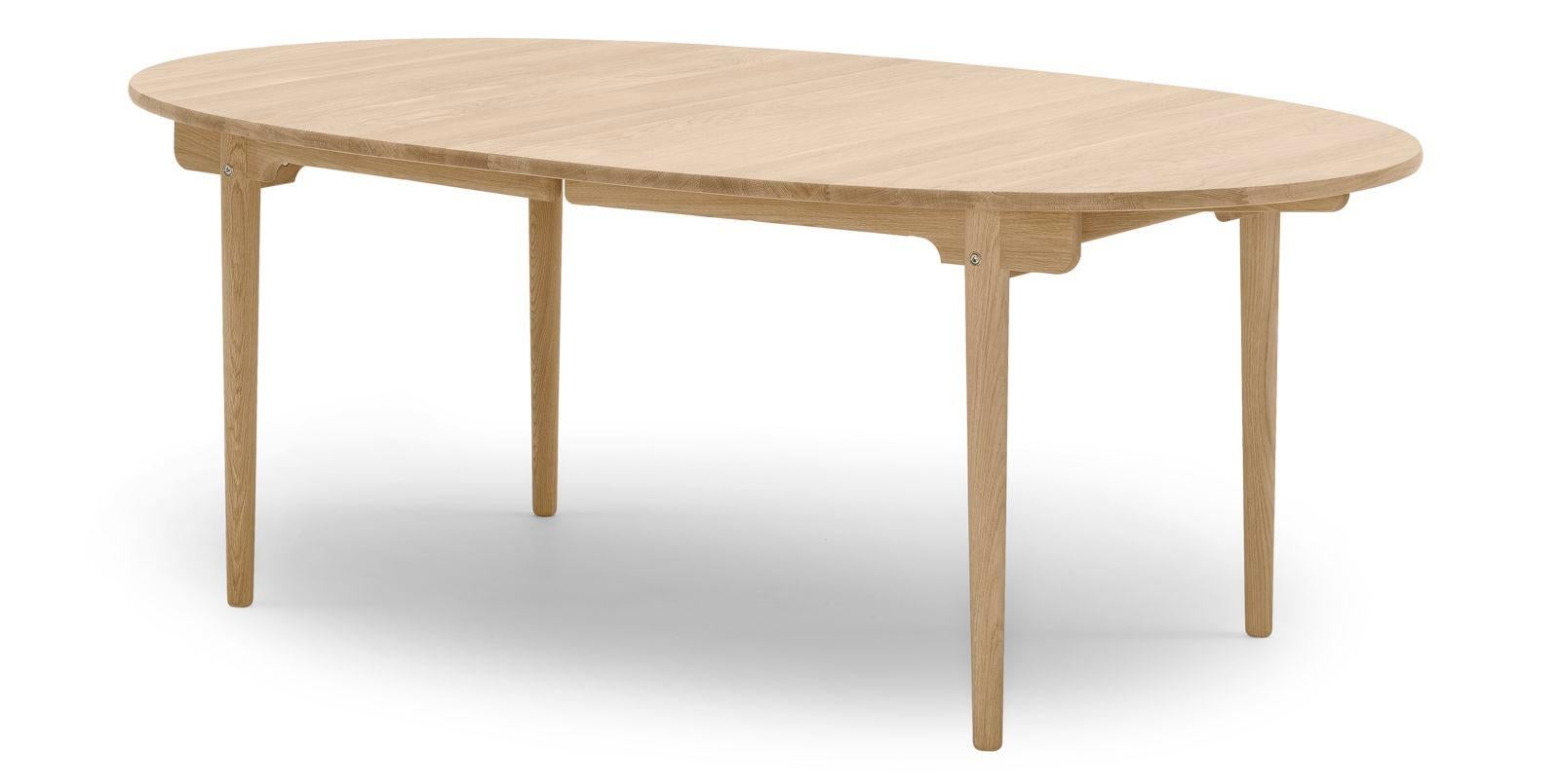 The CH338 Dining Table, designed for 6 people, is a longer version of Hans J. Wegner’s CH337 4-person dining table from 1962. Like the CH337, the CH338 has an elliptical-shaped tabletop that can be extended with leaves when more seats are needed.