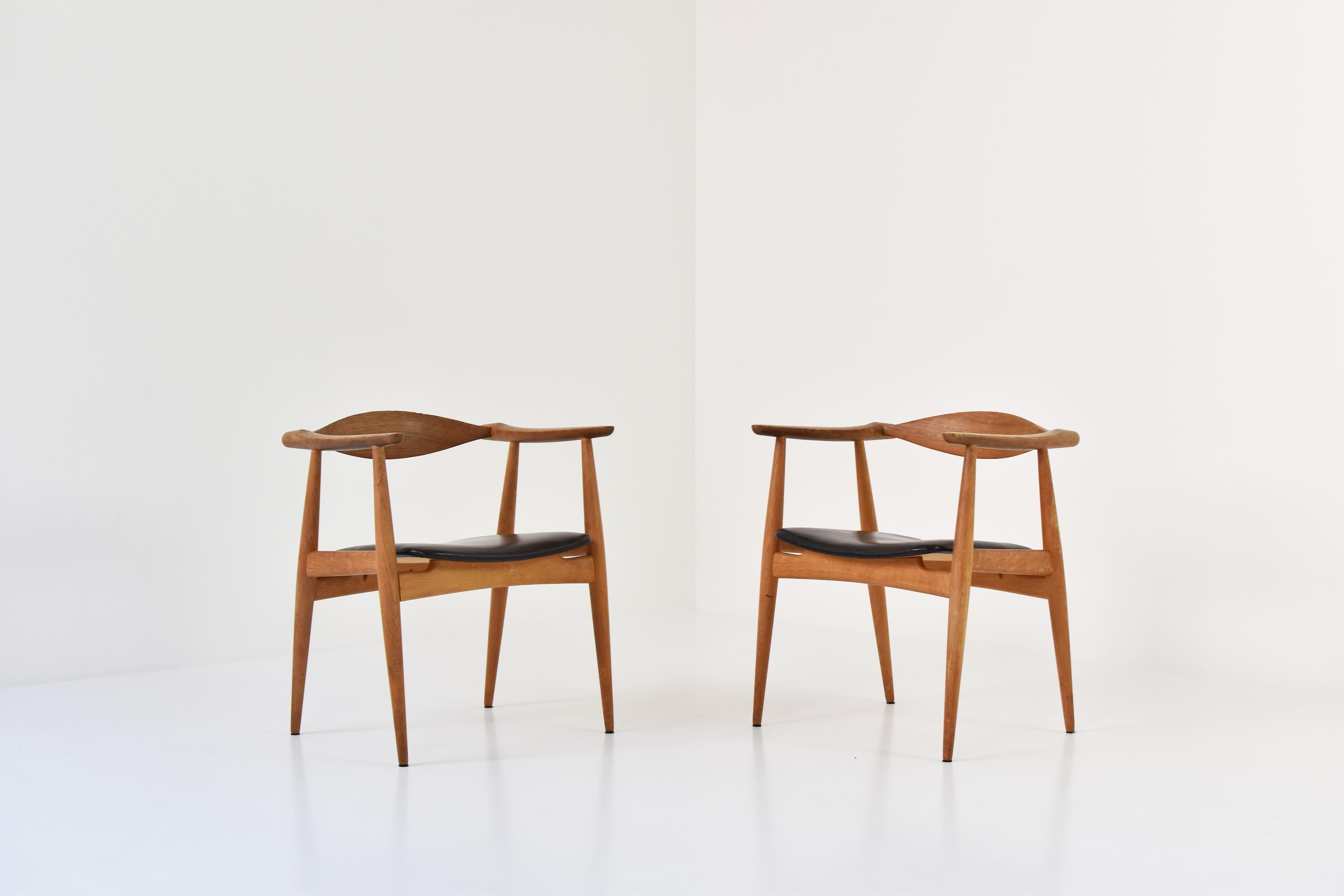 An amazing pair of CH35 chairs designed by Hans Wegner for Carl Hansen and Son, Denmark, 1950s. These sculptural armchairs features oak frames with the original (lovely) patinated black leather seats. Labeled underneath. Masterpiece!