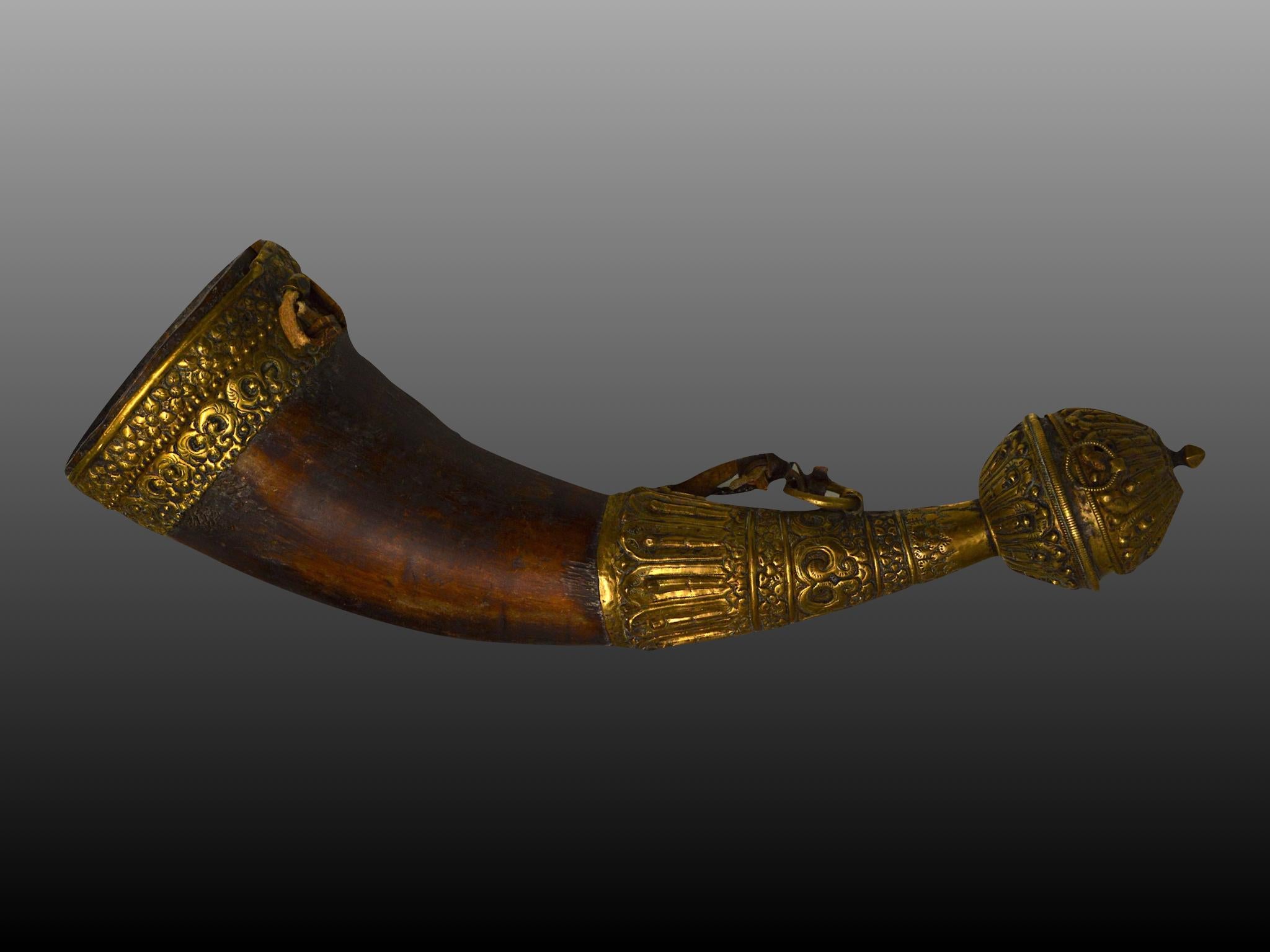 Tibet, greater Himalayas, circa 19th century. Horn mounted in gilded copper decorated with lotus petals. The yak horn has a natural curved shape and a small funnel for filling the horn at the end. The fittings are decorated with wave-and
