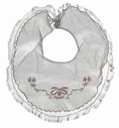 Aliboo Bib: Stilllebenfotografie von weißen und rosa bestickten Kinderkleidung in Weiß und Rosa