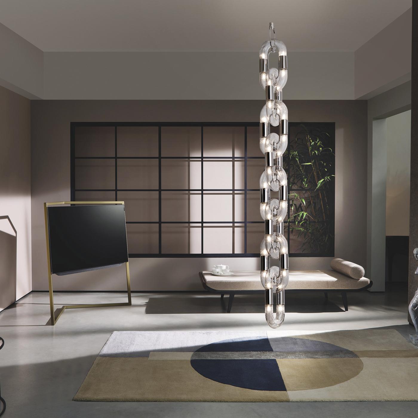 Masterfully merging metal and lighting need, Stillux's designers created a sophisticated chandelier of unparalleled contemporary allure. Its silhouette comprises eight interlocking links that serve as diffusers in transparent glass hosting each four
