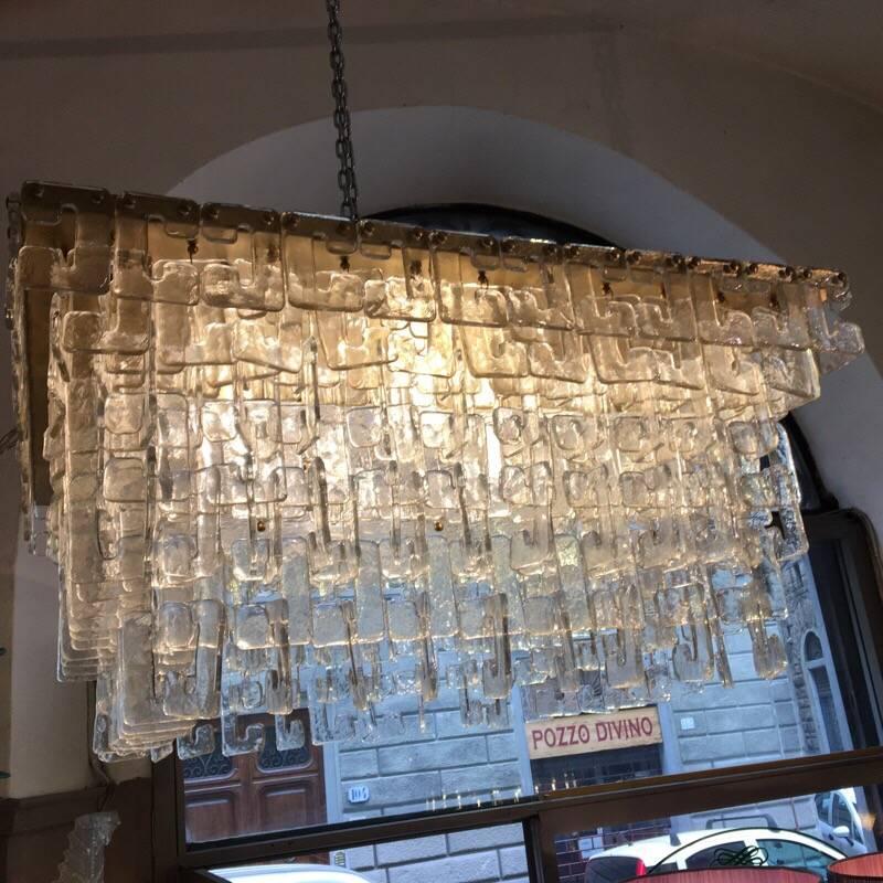 Chain link Murano C-shaped clear glass chandelier and brass structure.
The hand blown clear glasses hook on each other with waterfall effect.
The chandelier weighs about kg 100 and it has four light bulbs.
  