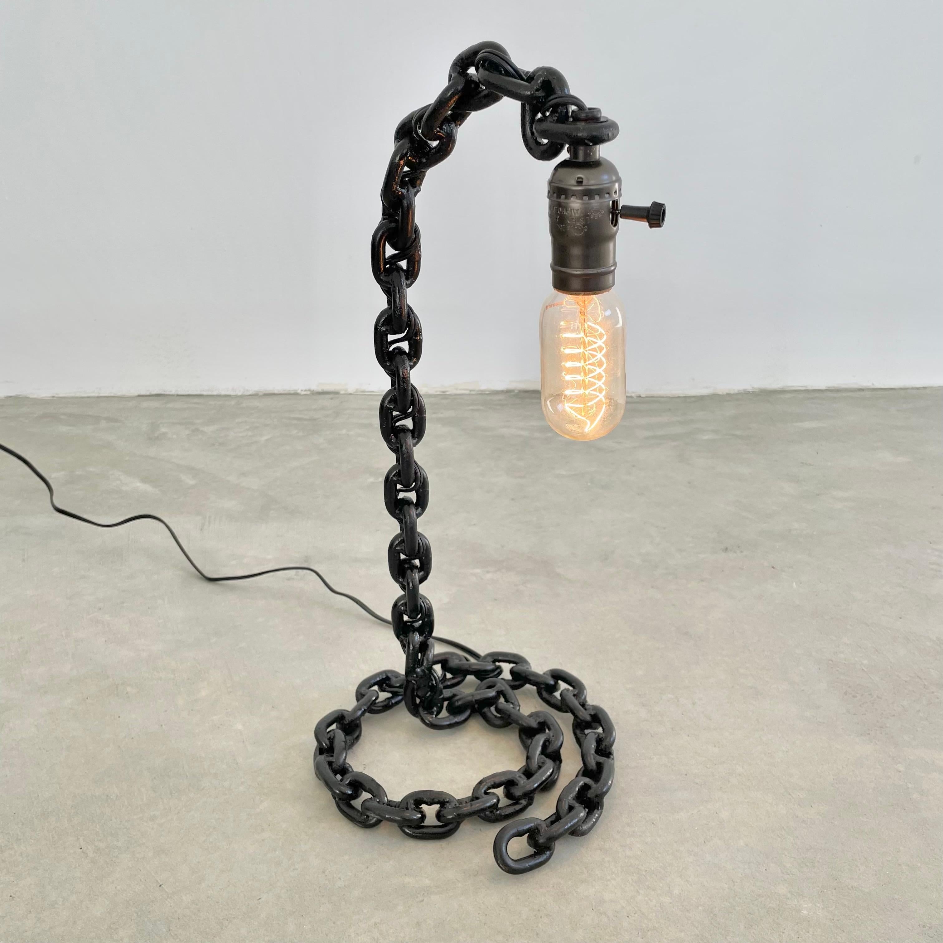 Brutalist chain link table lamp featuring a newly rewired socket. Rustic metal chain links welded together and painted in a jet black give this piece a commanding presence. Perfect to give your space that touch of contrast or to go along with a more