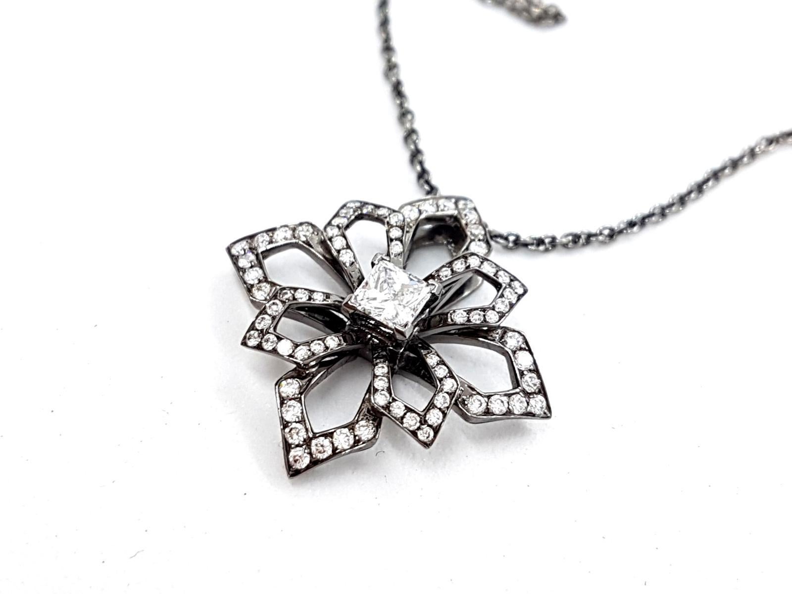 Beautiful fine jewelry necklace. black gold 750 thousandths (18 carats). flower pendant with diamonds for 0.78 ct in total. with a central diamond princess cut F-VS about 0.27 ct and paving 72 round brilliant cut about 0.51 ct total dimensions of