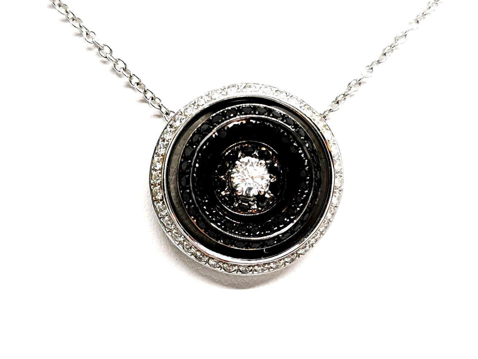 white gold necklace 750 thousandths (18 carats). pendant round. set in the center of a white diamond. brilliant cut approximately 0.18 ct. surrounded by 62 black diamonds totaling about 0.37 ct. and 37 white diamonds totaling about 0.22 ct. diamonds