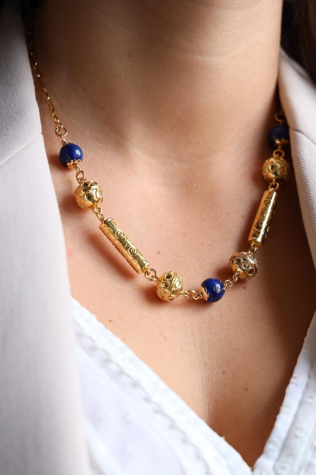 Necklace in yellow 820 thousandths (22 carats). flexible articulated mesh. 3 pearls of lapis lazuli of approximately 1.01 cm of diameter. 4 balls in yellow gold of approximately 1.25 cm of diameter. 2 cylinders in yellow gold of approximately 2.55