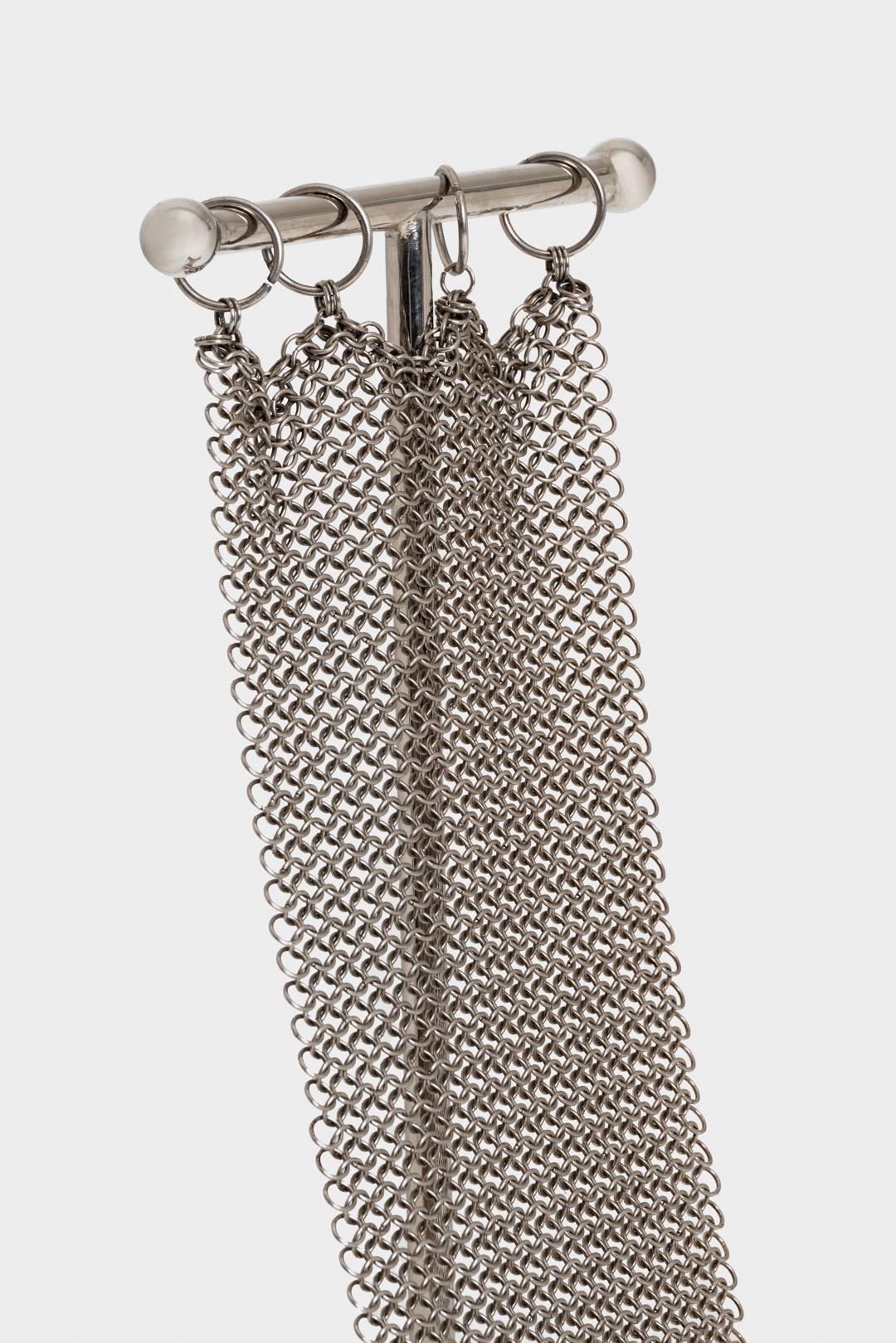 Chainmail Chair est une nouvelle version de la chaise en T de William &New datant de 1952. Son siège
est constitué d'anneaux de métal reliés à la main et formant un ensemble solide.
et d'une maille souple qui drape sa structure en T. Pour la chaise