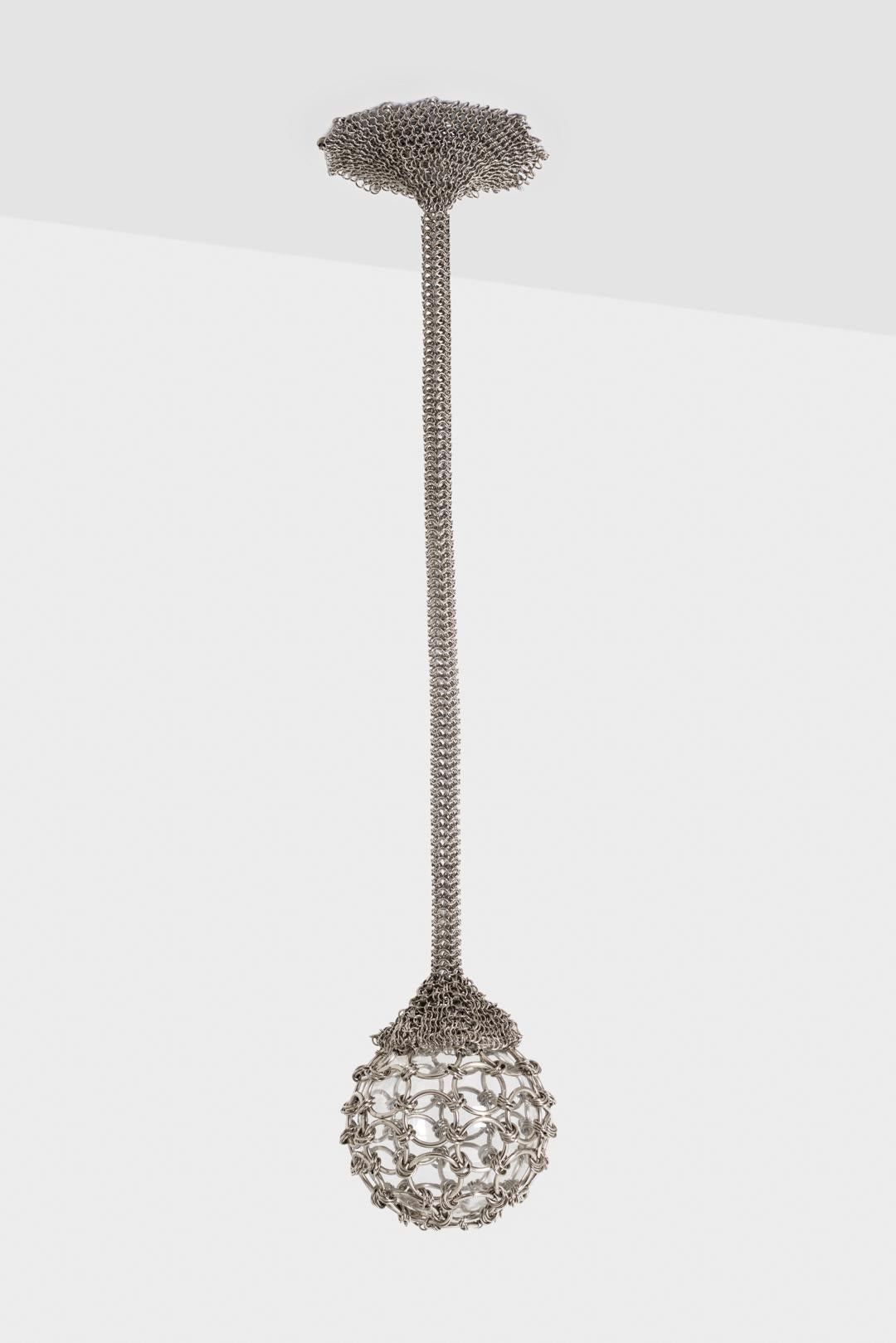 Il lampadario a gocce con ciondolo singolo è una bellissima lampada fatta a mano.
pezzo. Una rete di maglia metallica abbraccia il baldacchino della lampada.
buste di maglia in una corda che pende per sospendere infine un globo di vetro.
La fonte di