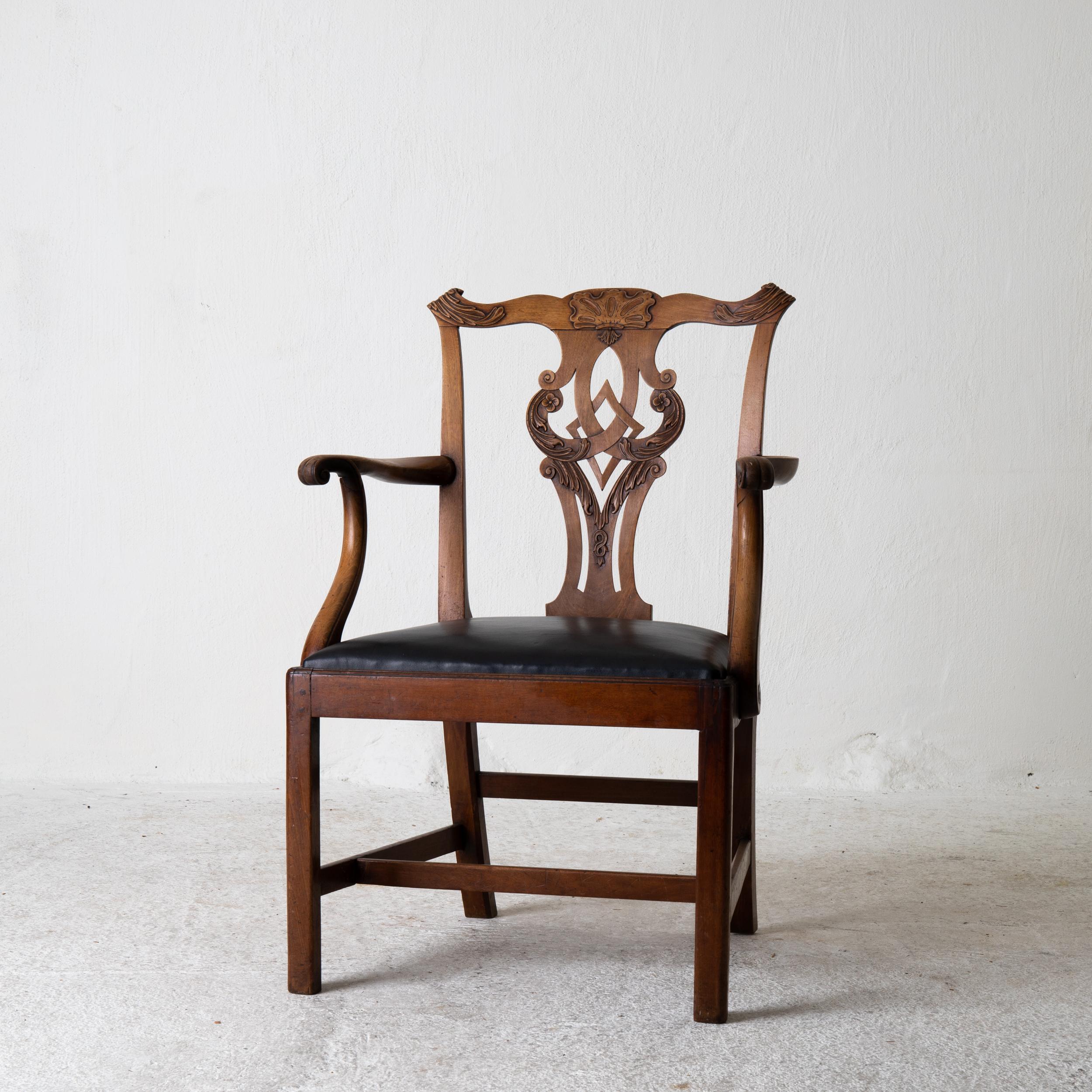 An armchair made during the 18th century and Chippendale period in England. Generous sized chair. Seat upholstered in black leather.