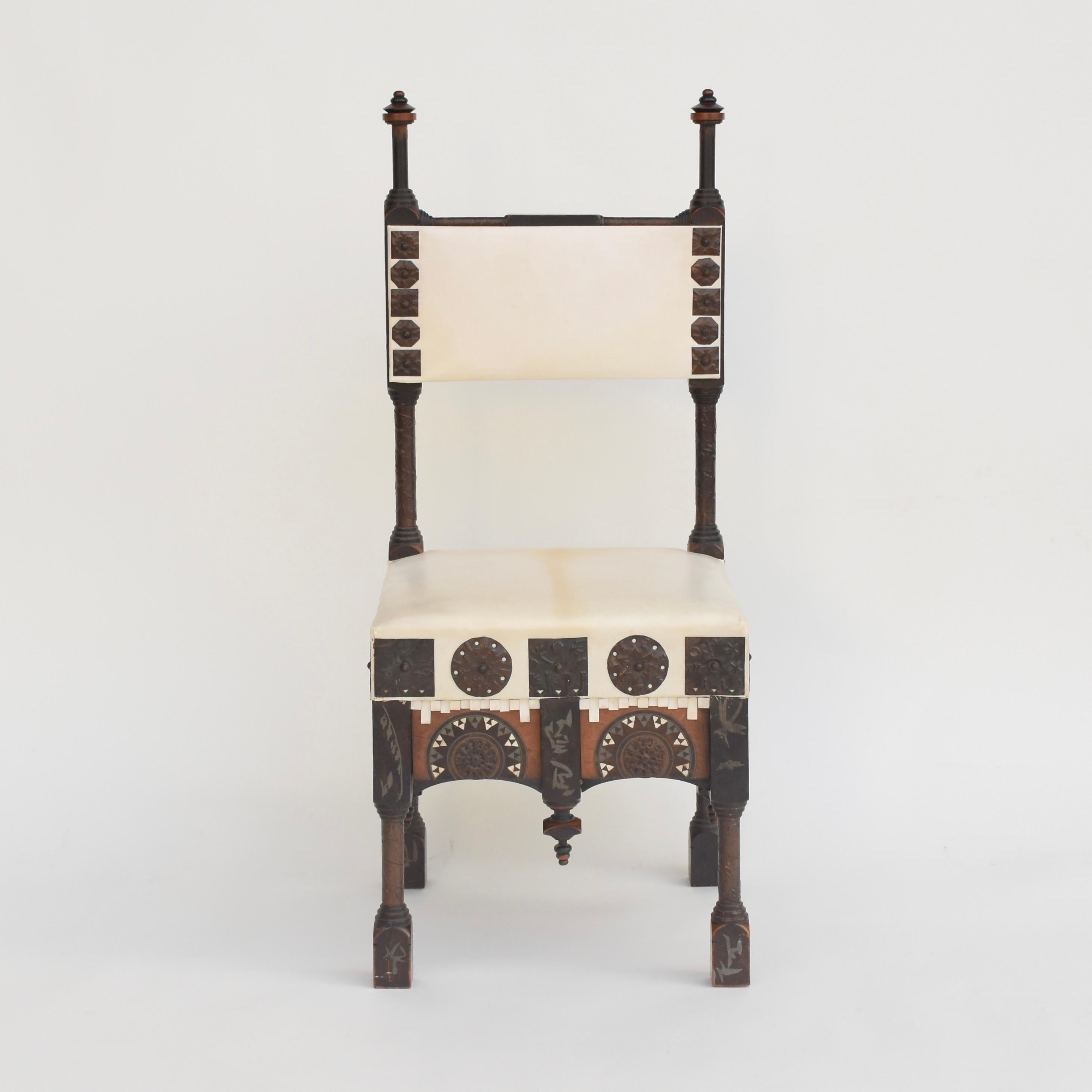 Magnifique chaise de Carlo Bugatti en bois partiellement ébonisé, ornée d'incrustations géométriques en métal et en os et de décorations en métal repoussé. Pieds et montants tournés recouverts de rubans de cuivre. Assise et dossier garnis de Vellum.