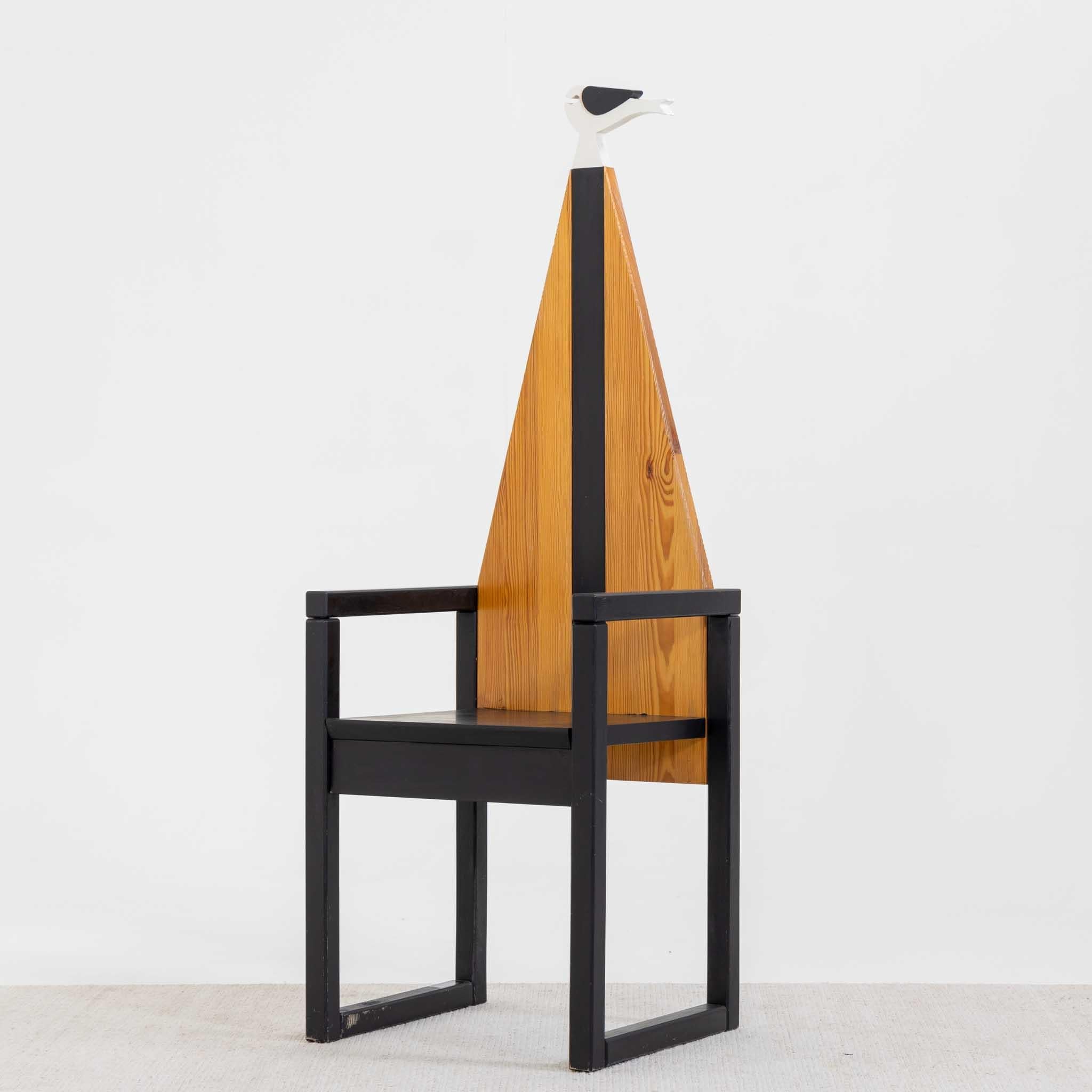 Chaise avec structure en bois noir de forme géométrique et dossier triangulaire en hêtre avec bande noire contrastée et oiseau stylisé en noir et blanc. Label Legnomagia Italie sur la base.