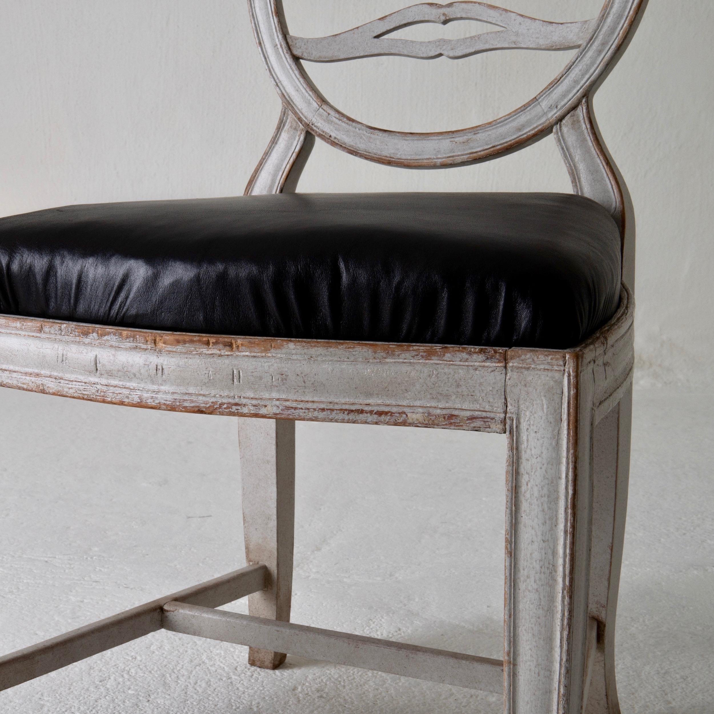 Chair Gustavian Swedish white black Sweden. A side chair made during the Gustavian period in Sweden 1790-1810. Beautiful carvings on the oval back. Square and tapered legs. Loose seat upholstered in a soft black leather.