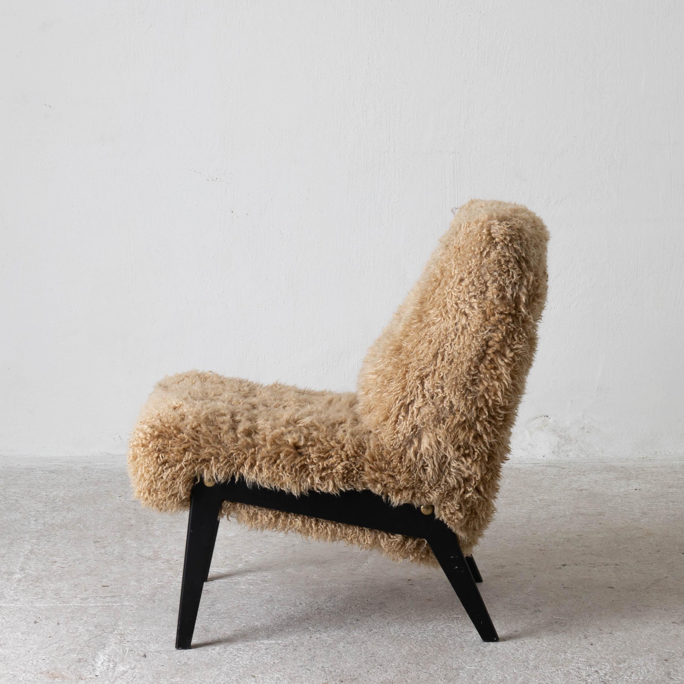 Chair Swedish Nordiska Kompaniet 20th century fur beige, Sweden. A lounge chair made during the 20th century by in Sweden. Reupholstered in a long haired golden colored fur. Black legs with brass screws.