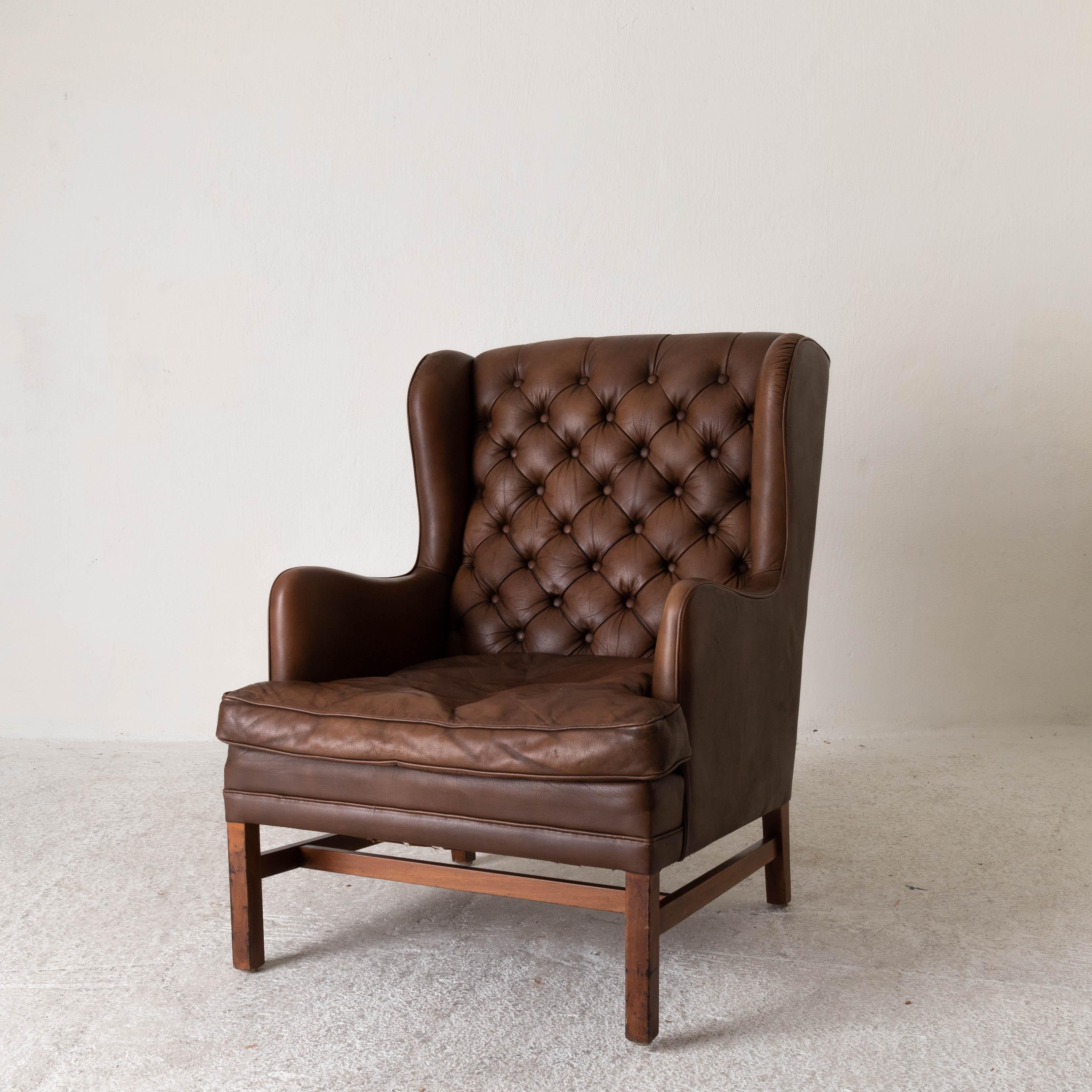 Chair wingback Swedish 20th century brown tufted, Sweden. A larger wingback chair made during the 20th century in Sweden. Upholstered in a brown leather with a tufted back. Square wooden legs.