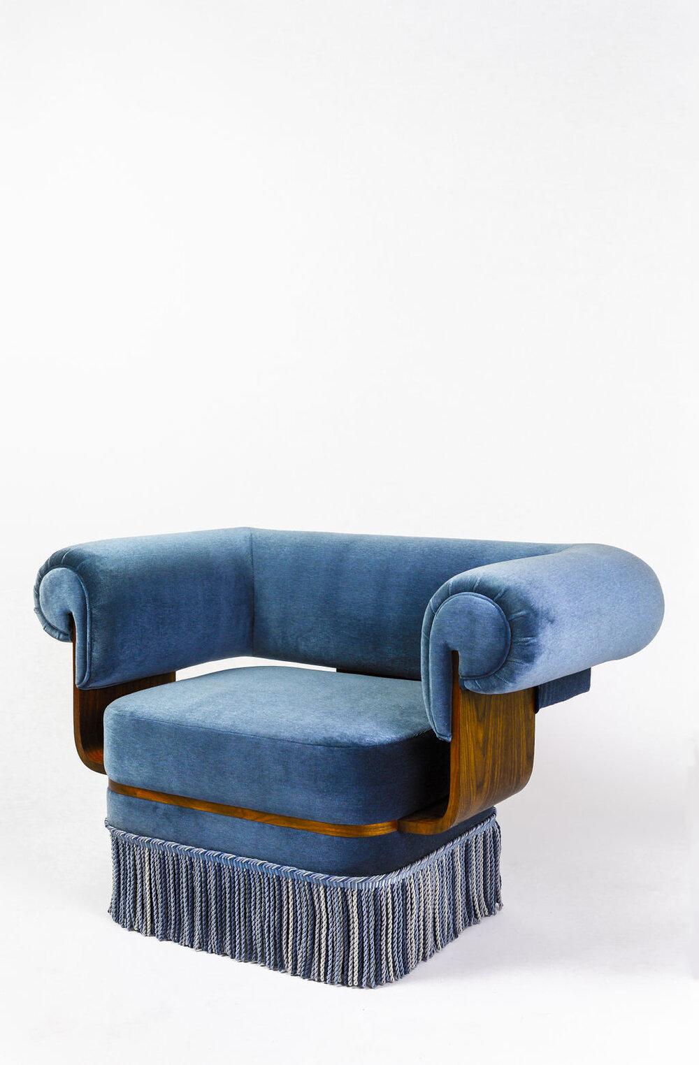 The Morris armchair features bent walnut wood that accents the curved upholstery. The chair proves to be perfect for lounging with a large seat and comfortable arms. The chair is upholstered in blue mohair and completed with 8.25” silk bullion