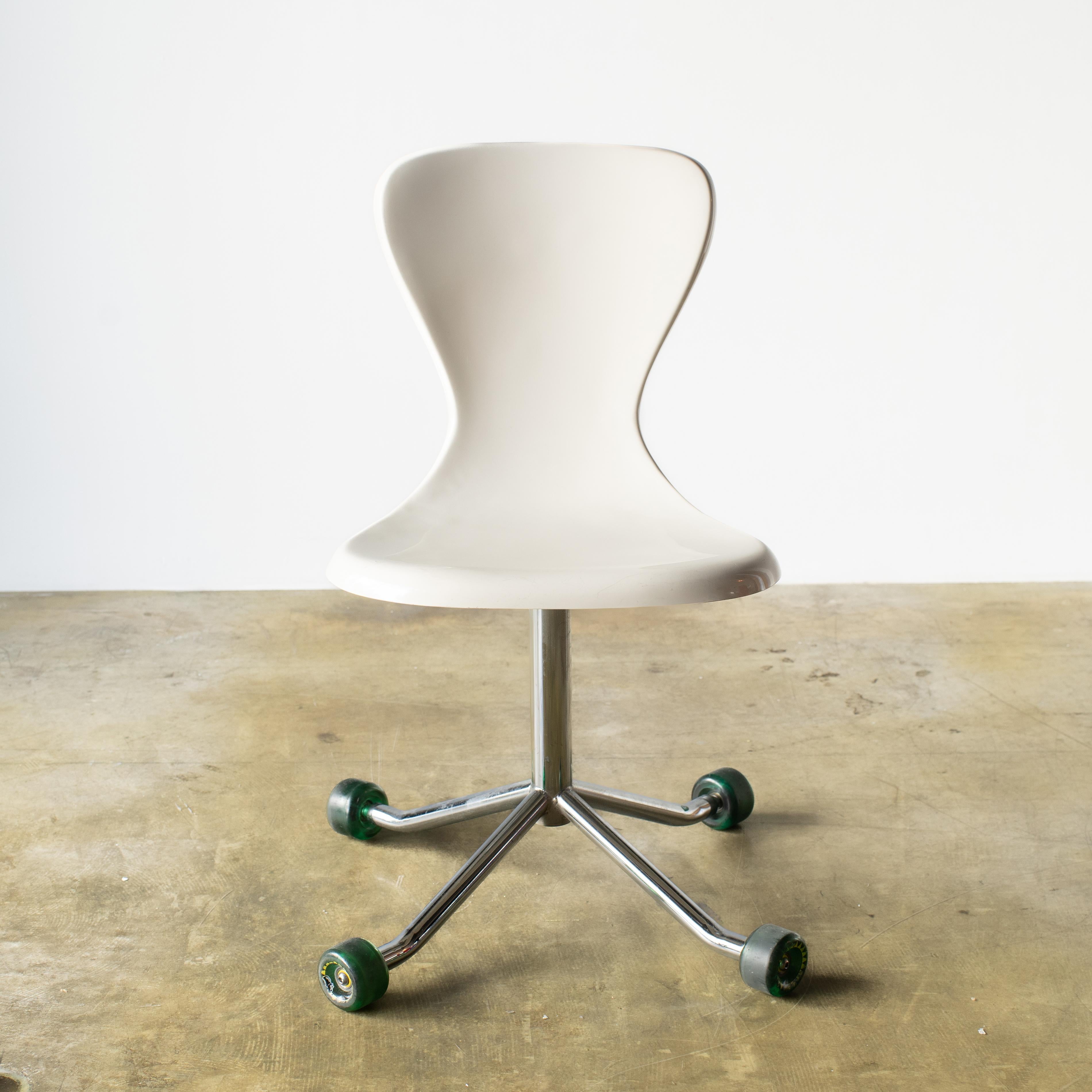 Drehbarer Schreibtischstuhl mit Skateboard-Rädern.  Es ist ein lustiger Stuhl, der sich auf vier Rädern drehen kann.  
Das ist der Stil der Jahr-2000-Einrichtung und des Designs. Auch ein wirklich tolles Beispiel aus dieser Zeit. 
 