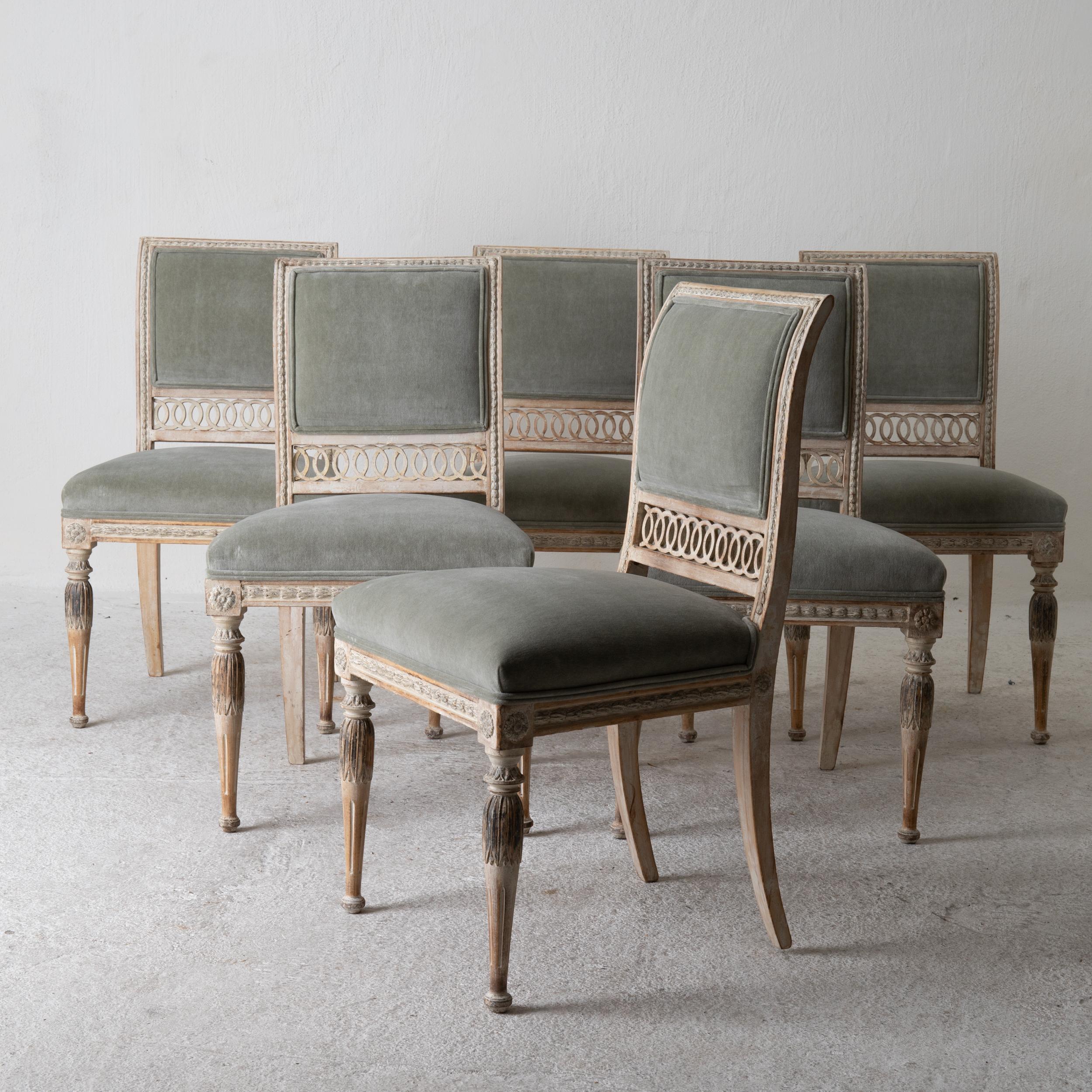 A set of dining chairs made during the Gustavian period 1790-1810 in Sweden. Beautifully carved frame and stripped to its original finish. Rounded and channeled legs. Upholstered back and seat in a light green cotton velvet. 

 