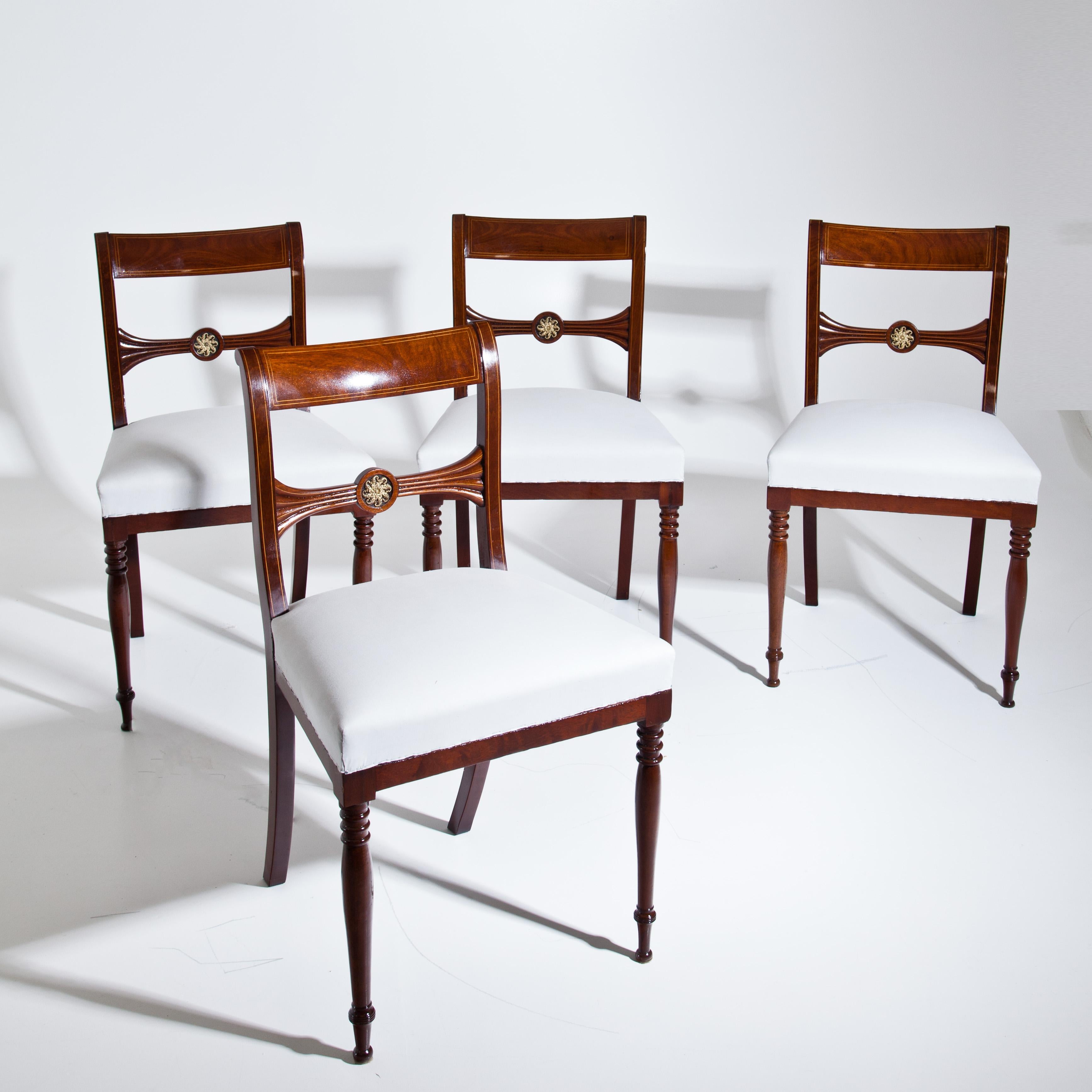 Set of four mahogany chairs with thread inalys and s-shaped backrests with gilt ornaments in the shape of cornucopias on the middle slat. The chairs stand on bent rear legs and baluster shaped front legs. The chairs are in a restored condition and