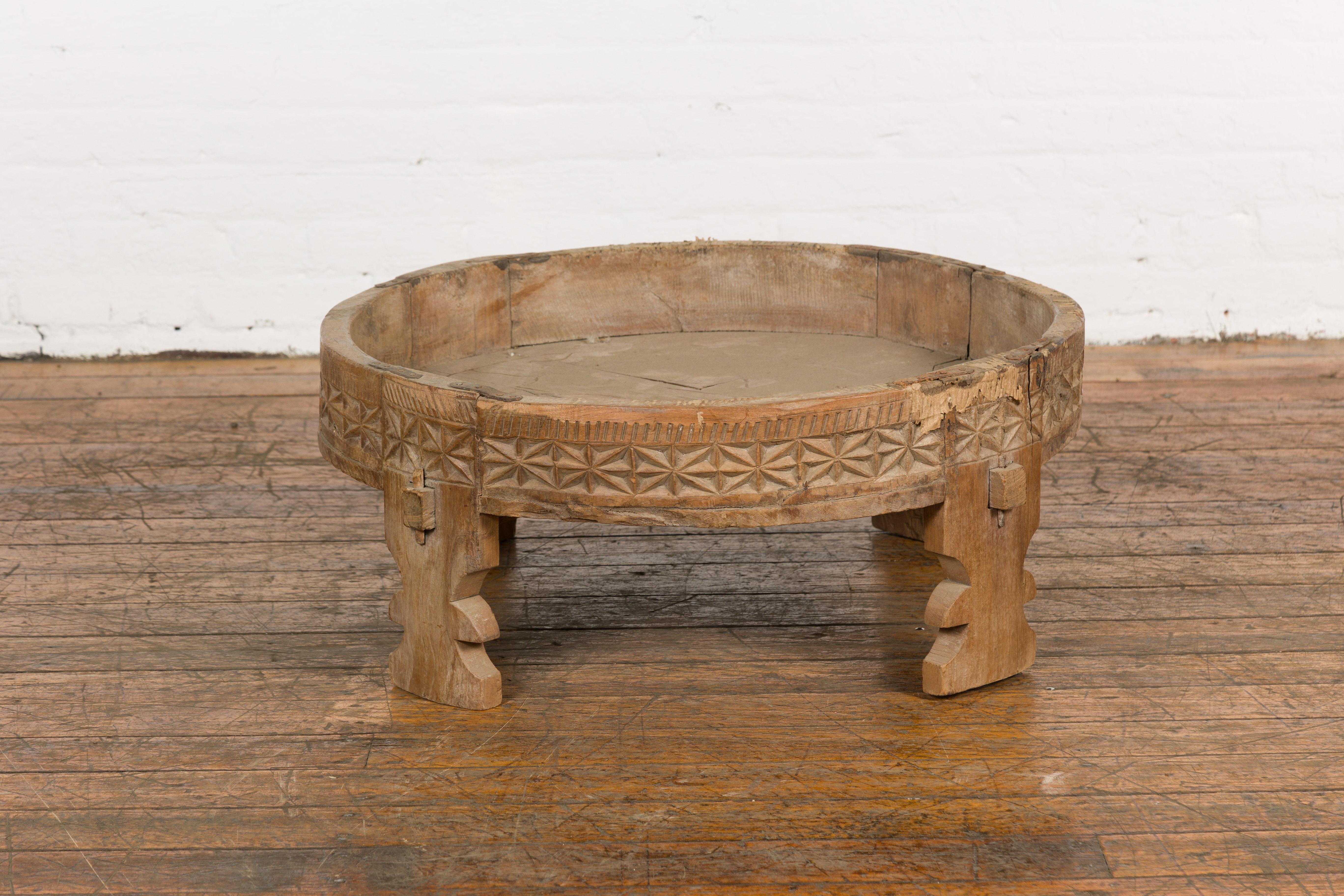 Table de broyeur Chakki rustique d'Inde tribale du début du 20e siècle avec des motifs géométriques sculptés à la main, des pieds sculptés et une patine vieillie. Créée en Inde dans les premières années du 20e siècle, cette table de broyage est