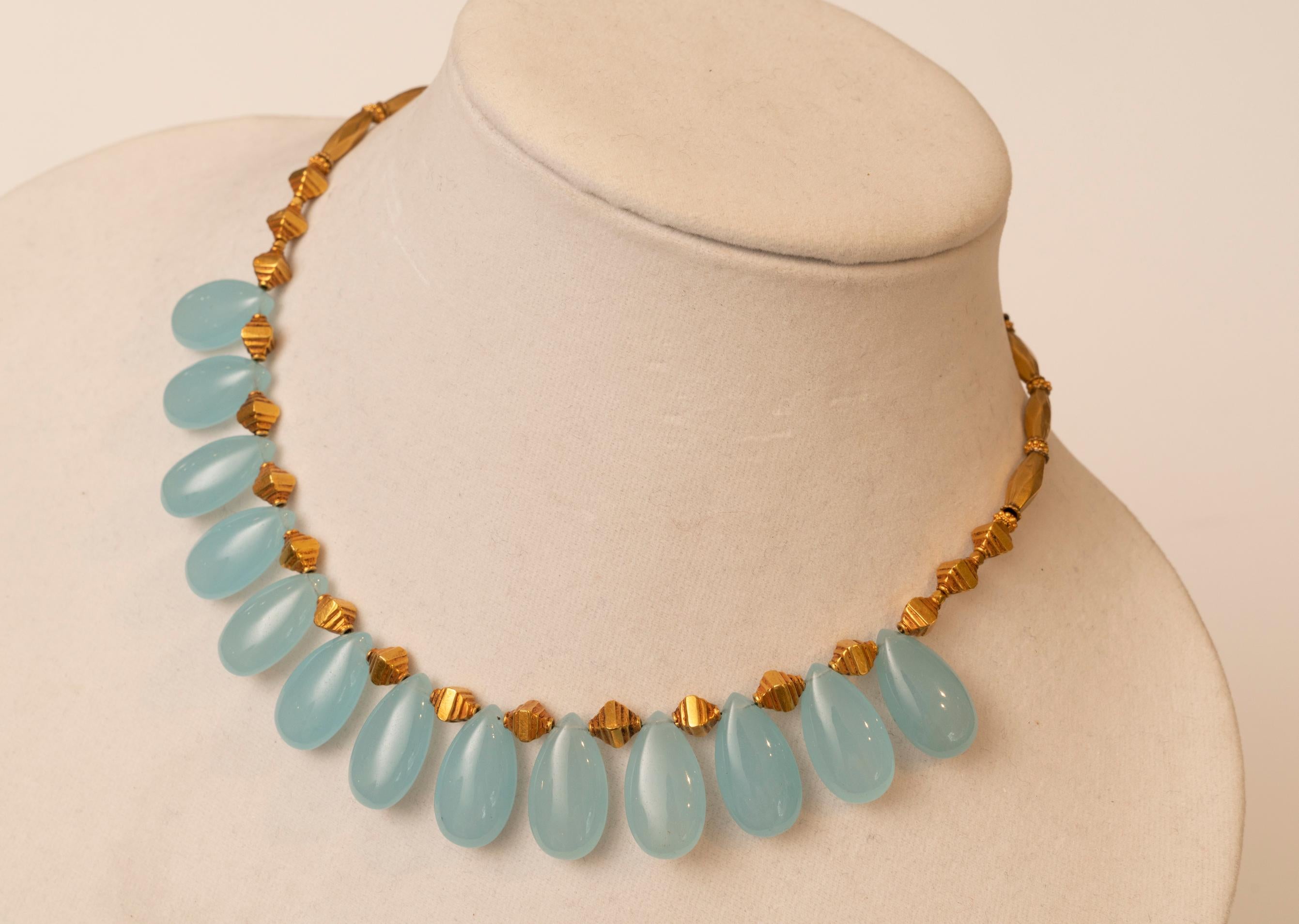 Stunning pear-shaped light blue chalcedony drops spaced with textured and turned 18K gold beads with an S-hook clasp at the back.  The chalcedony beads themselves measure 7/8 inches long and 7/16's wide.  This can be worn on an open neckline or