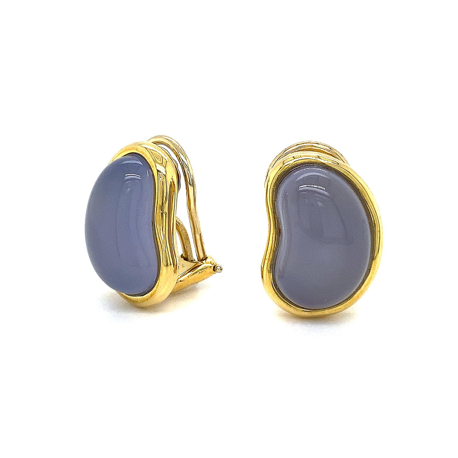 Distinct blue gray tones of chalcedony are highlighted in a bean-shaped carving. The curve of the crystalline gemstone is turned inward. Set in 18k yellow gold, a touch of color and shimmer accentuates the chalcedony. The clip-back earrings measure