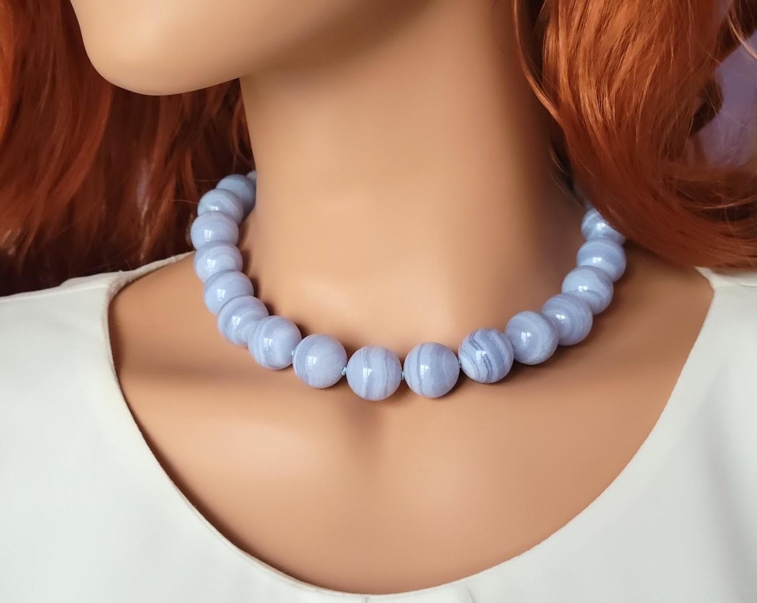 Die Länge der Halskette beträgt 17,5 Zoll (44,5 cm).
Die Größe der glatten runden Perlen beträgt 16 mm.
Blauer Achat und Blauer Spitzenachat sind austauschbare Bezeichnungen für die gleiche Art von gebändertem Chalcedon, der zur Familie der