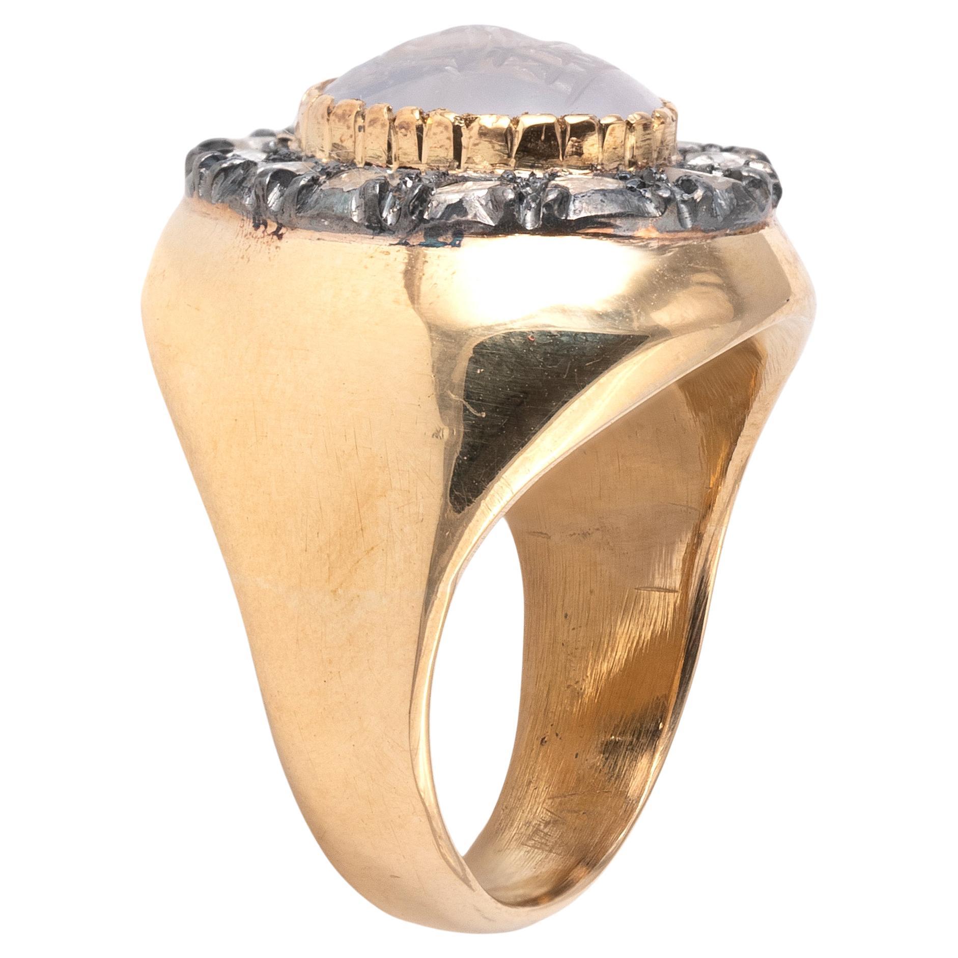 Ring aus Silber, Gold und rosafarbenem Diamant mit Intarsien aus blassblauem/grauem Chalzedon, der Jupiter auf seinem Thron sitzend zeigt, der einen Donnerkeil hält und zu dessen Füßen ein Adler sitzt.
In der Antike wurden dem Chalzedon