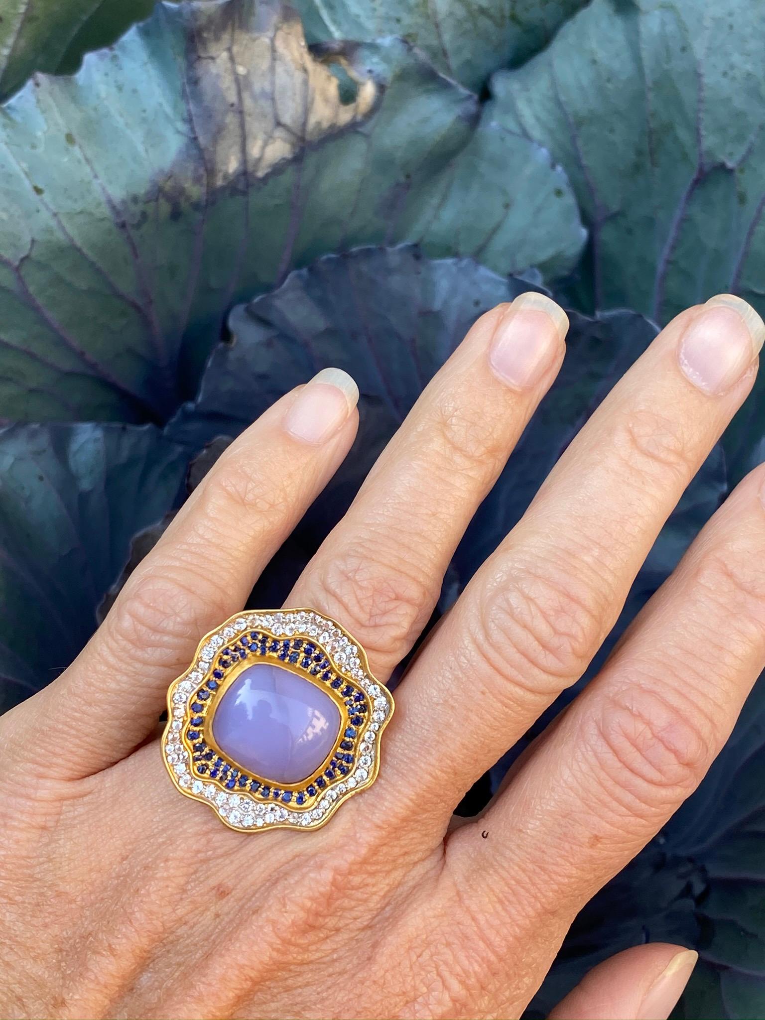 Designed by award winning jewelry designer, Lauren Harper, this Lavender Chalcedony cabochon center stone ring is surrounded by blue and white faceted sapphires and set in 18kt Gold. Extremely comfortable to wear. Sits with a low profile on the