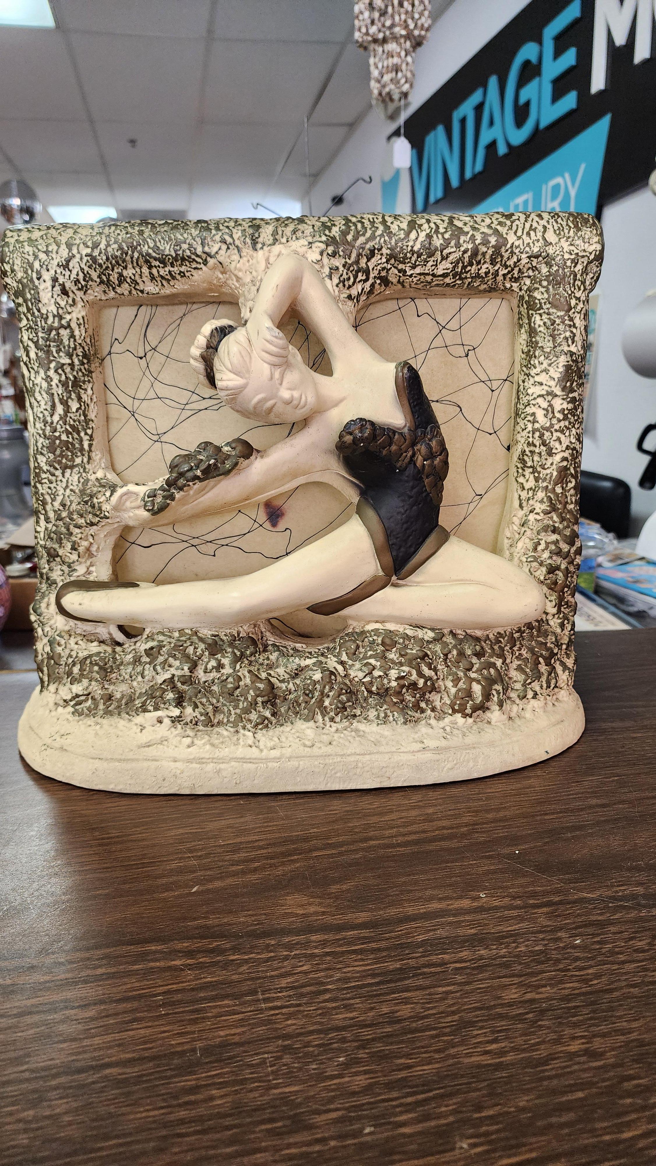 This incredible lamp from the 1950s is by N.Y.S. It depicts a ballet dancer with black tutu and bun in her hair in full leap. The light comes from the back and glows through the decorated vellum. The frame around the vellum is contoured chalkware