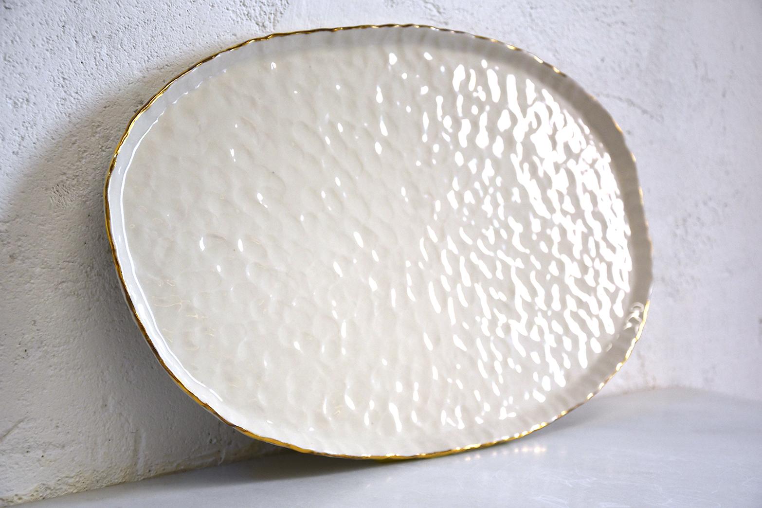 This pinched white porcelain plate by Isabel Halley was made specifically for Challah but can be used as a decorative platter for anything you would like to enjoy. Each platter is made by hand and no two are exactly alike. 22-karat gold luster