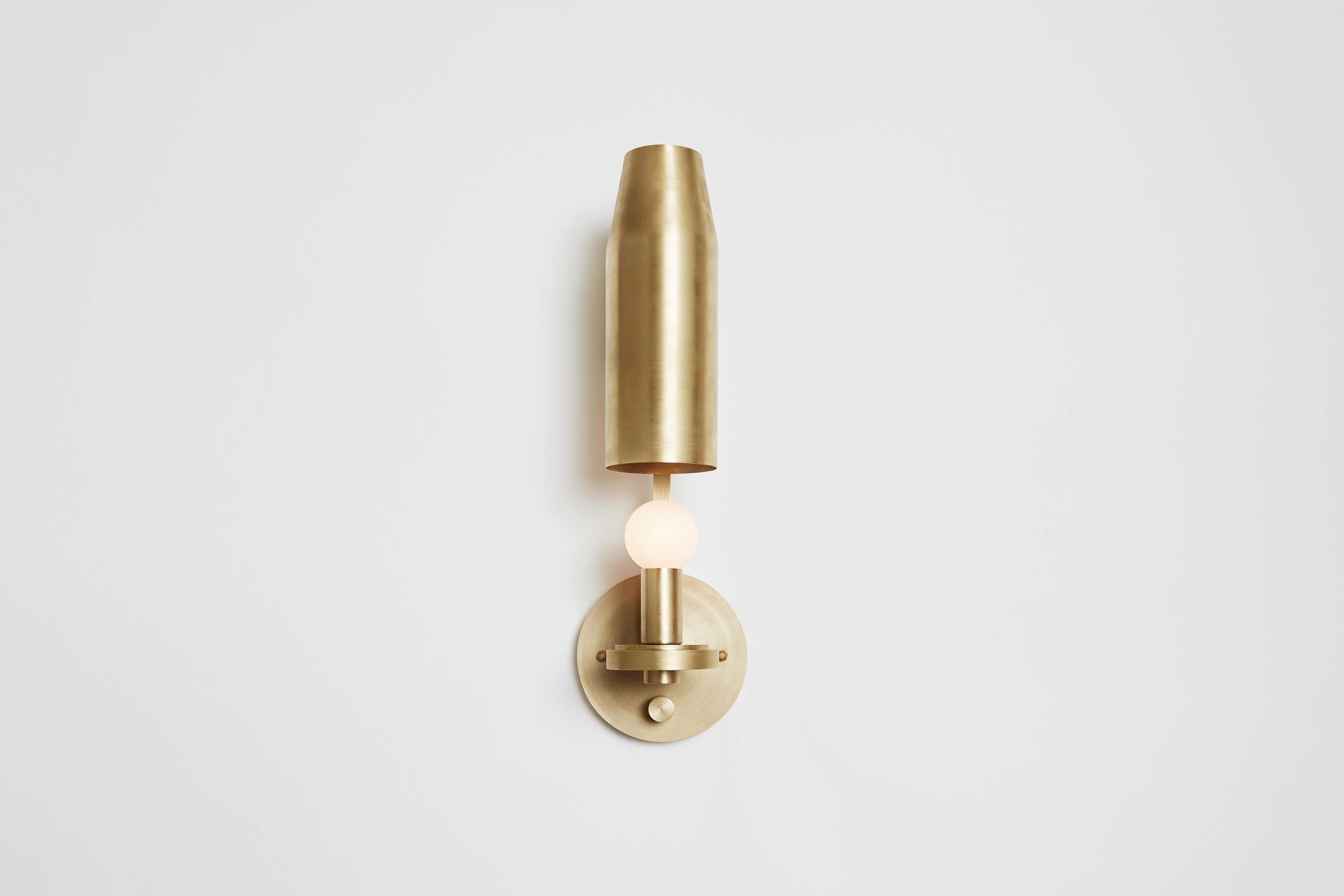 The Chamber Sconce features an adjustable metal shade that conceals or reveals light by degree. Composed of square brass tubing supporting a sculptural shroud, the fixture is suitable for myriad applications given its adaptable nature. Features an