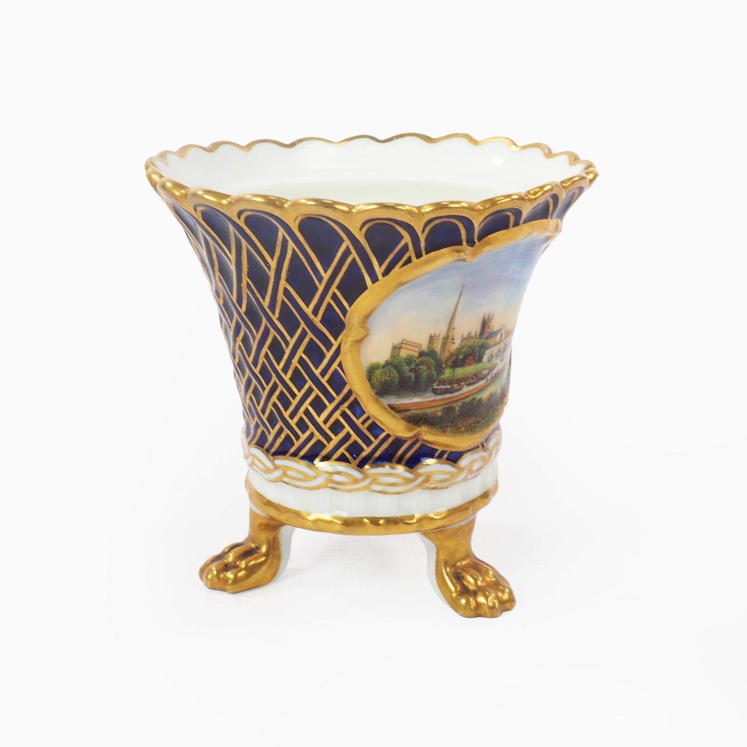 Chamberlain Worcester three footed porcelain pot or vase of the French style decorated with gilded lion’s feet and cobalt and gilt trellis with a hand painted panel depicting a view of the city of Worcester and its cathedral. Signed Worcester
