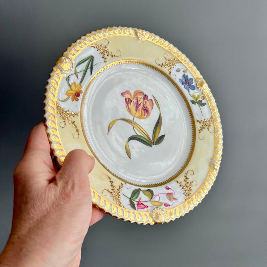 This is a stunning dessert plate made by Chamberlains Worcester between 1815 and 1820. The plate has a light yellow ground with beautiful flower reserves, and a striking yellow and red 