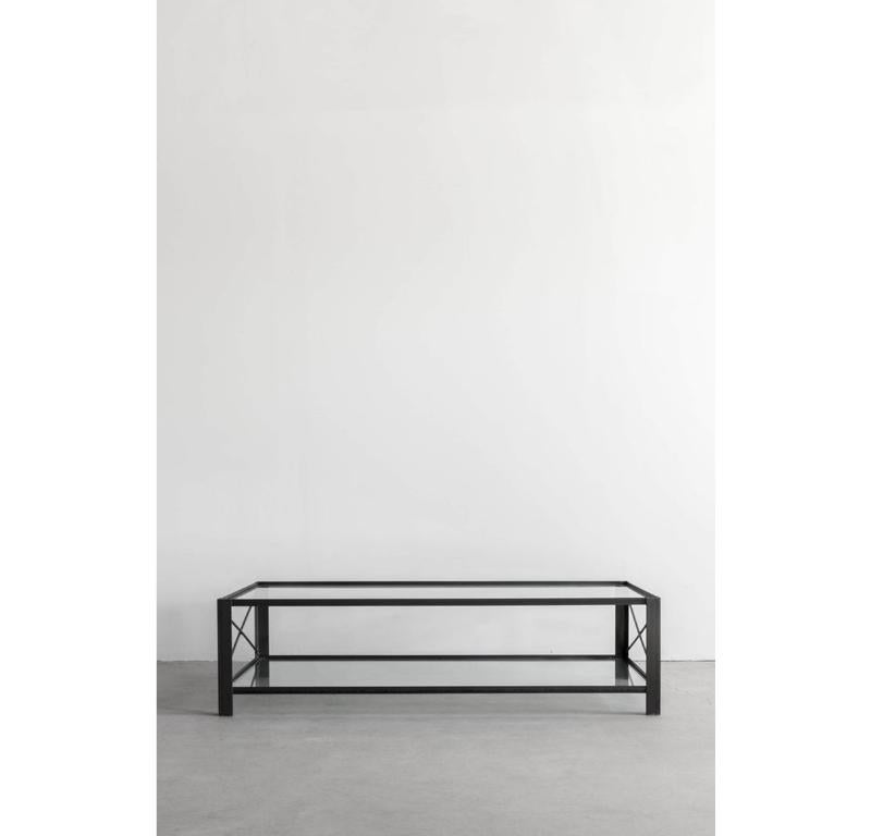 La table basse Chambers présente un arrière-plan industriel et minimaliste pour le style des tables basses. Son cadre en acier aux tons ardoisés accueille deux pièces de verre encastrées en guise d'étagère supérieure et d'étagère inférieure. Le