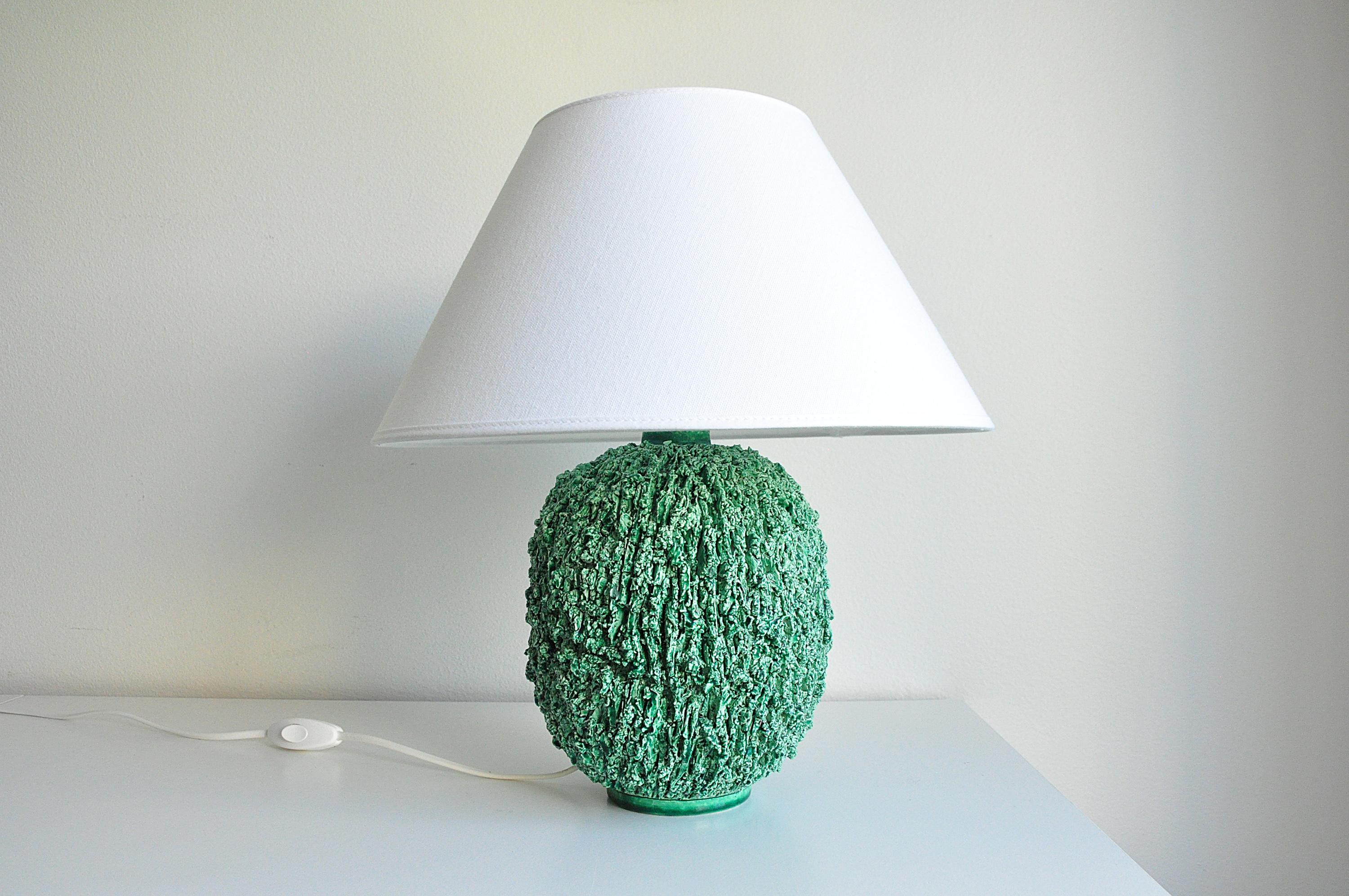 Lampe de table ''Chamotte'' de Gunnar Nylund pour Rörstrand.
La lampe est faite d'argile chamottée et finie avec une glaçure lustrée de couleur verte. New wiring, Please note : the shade is not included.