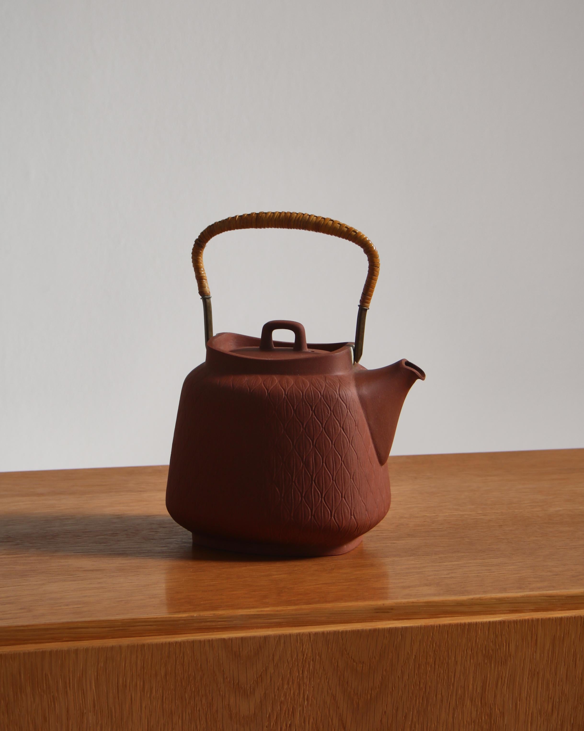 Wonderful teapot by Jens Harald Quistgaard in fired chamotte clay with handle of cane. Made at 