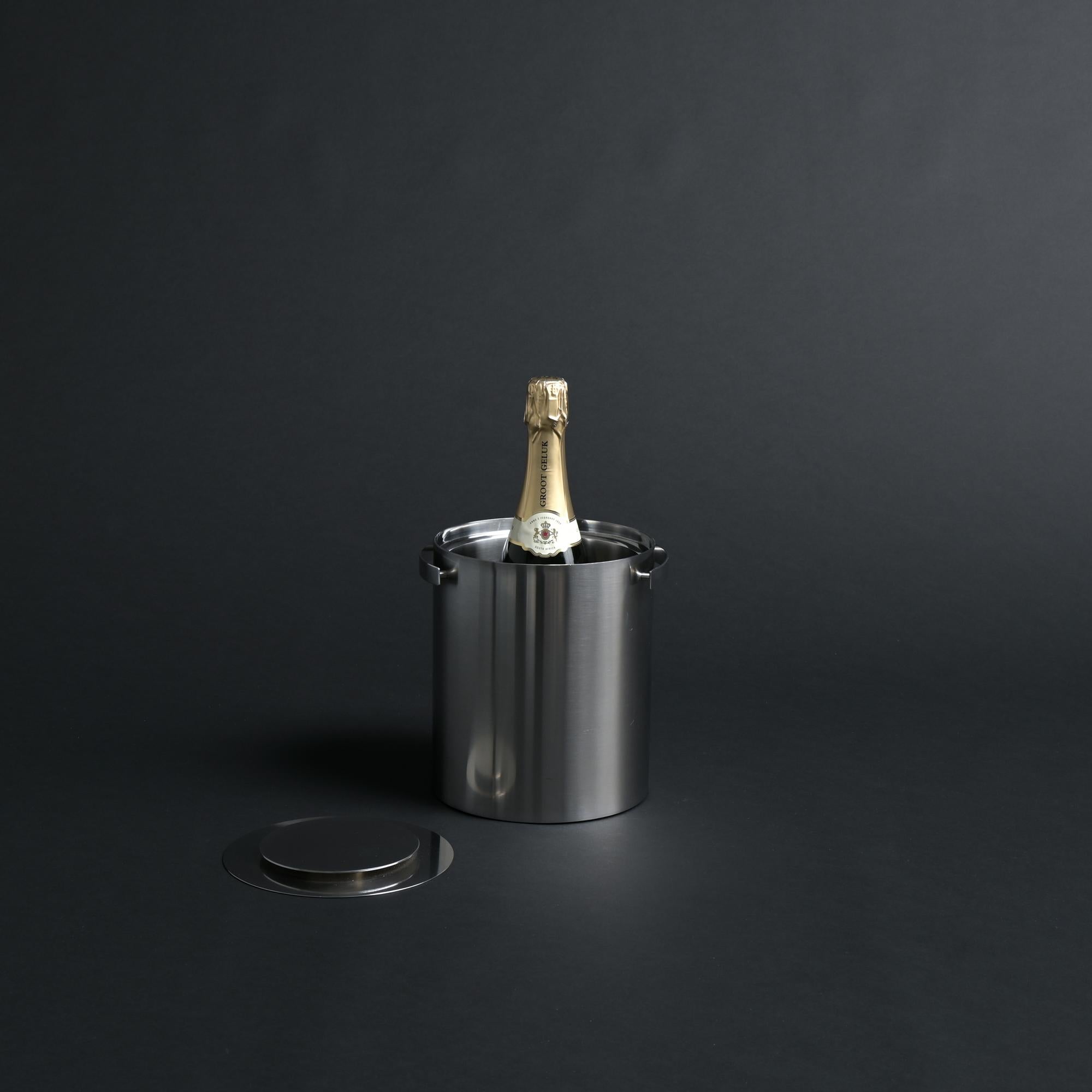 Around the 1980s Arne Jacobsen designs his iconic Cylinda line for the Danish manufacturer Stelton.

As a part of this line, a close relative to the ice buckets, follows this slightly taller champagne cooler.

This double-walled cooling bucket is