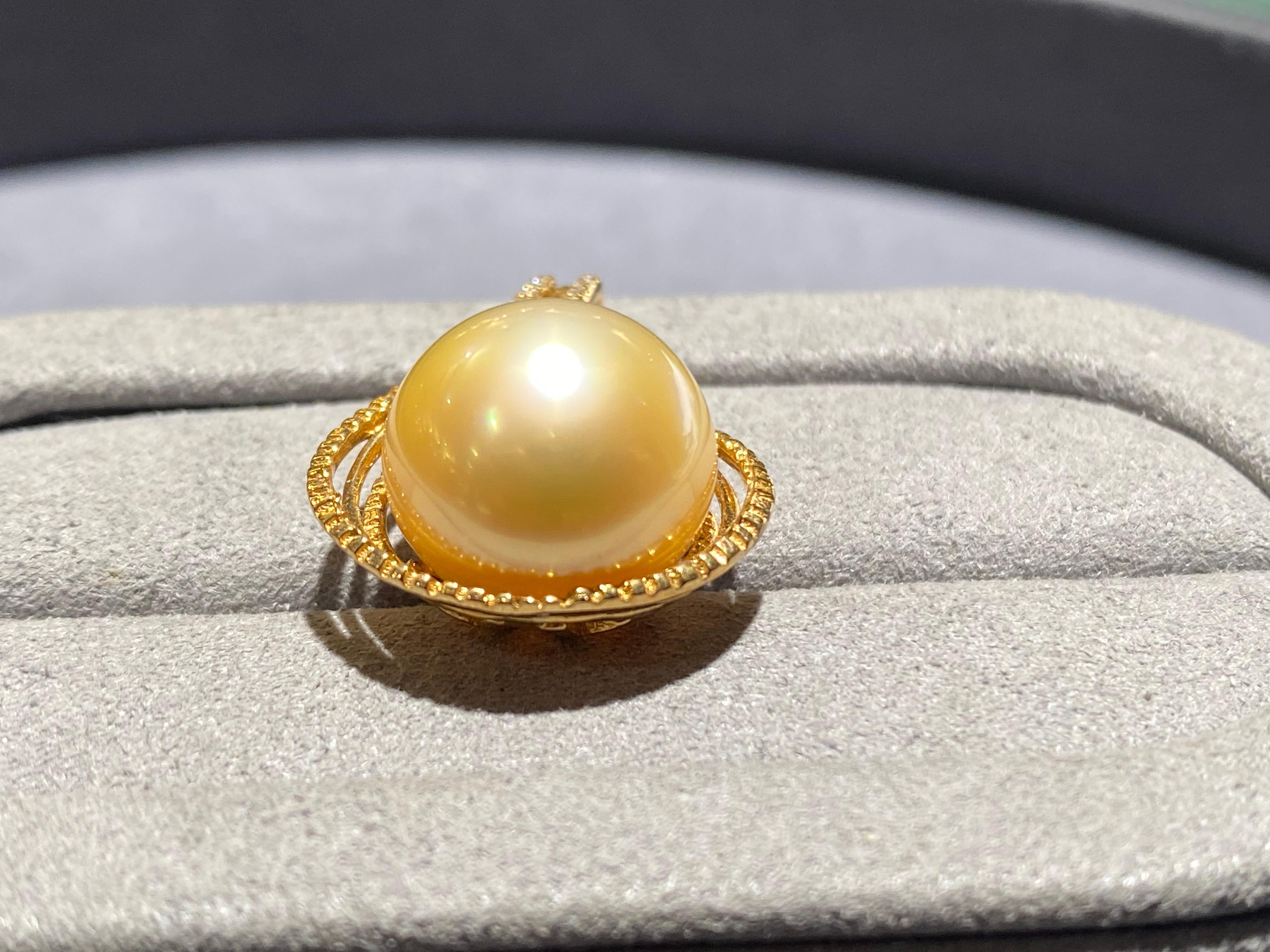 A round 13.2 mm champagne colour south sea pearl in 18k yellow gold. It is a rain drop pendant with a heart-shape ribbon near the bale end. It is a very simple pendant that is perfect for everyday wear. The colour of the pearl is champagne with