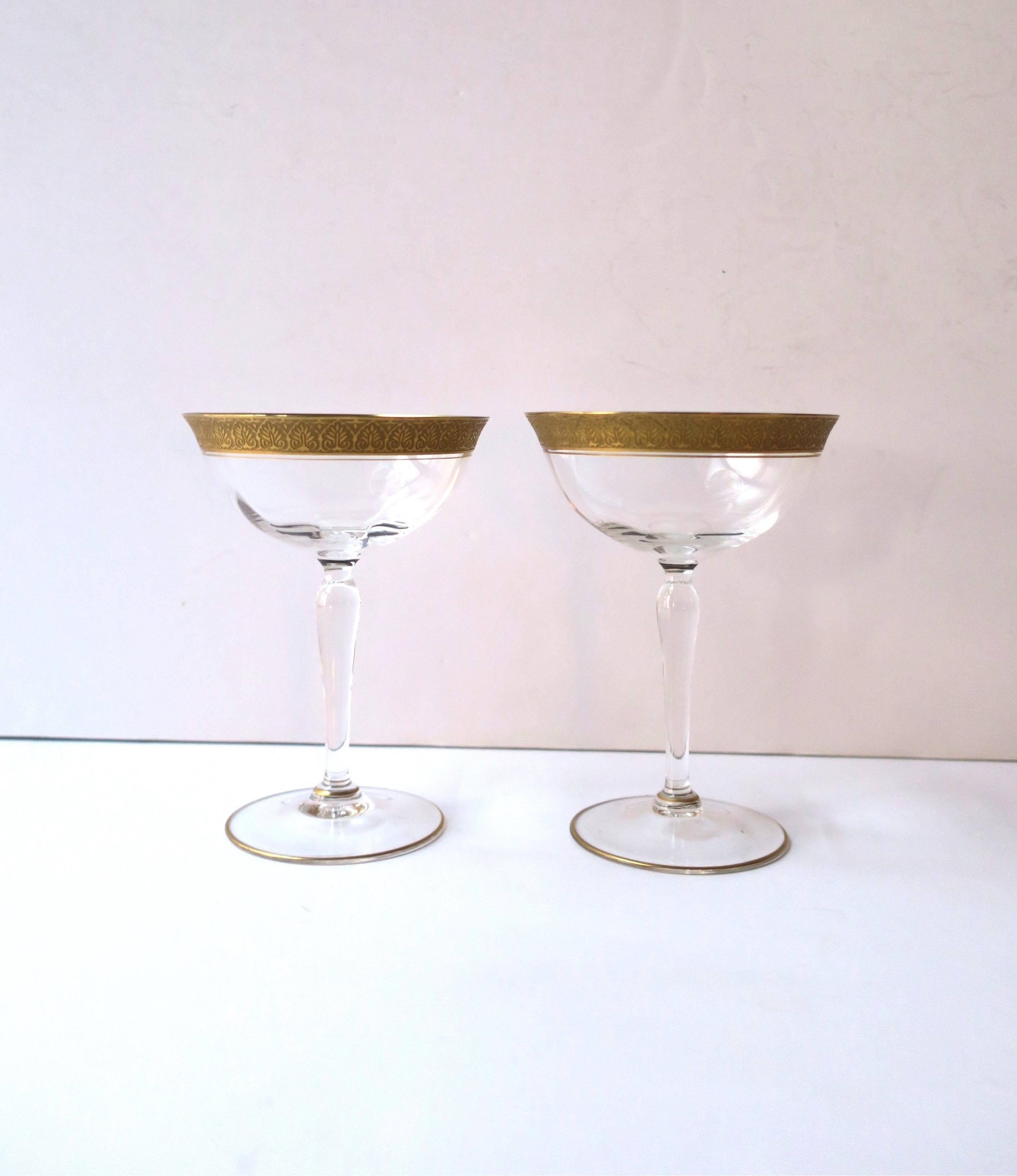 A beautiful pair of 22-karat gold rimmed Champagne or cocktail coupes glasses, circa early-20th century, Europe. Pair have a beautiful gold embossed exterior rim, gold interior rim, and thin gold edge around base. A beautiful set to enjoy Champagne