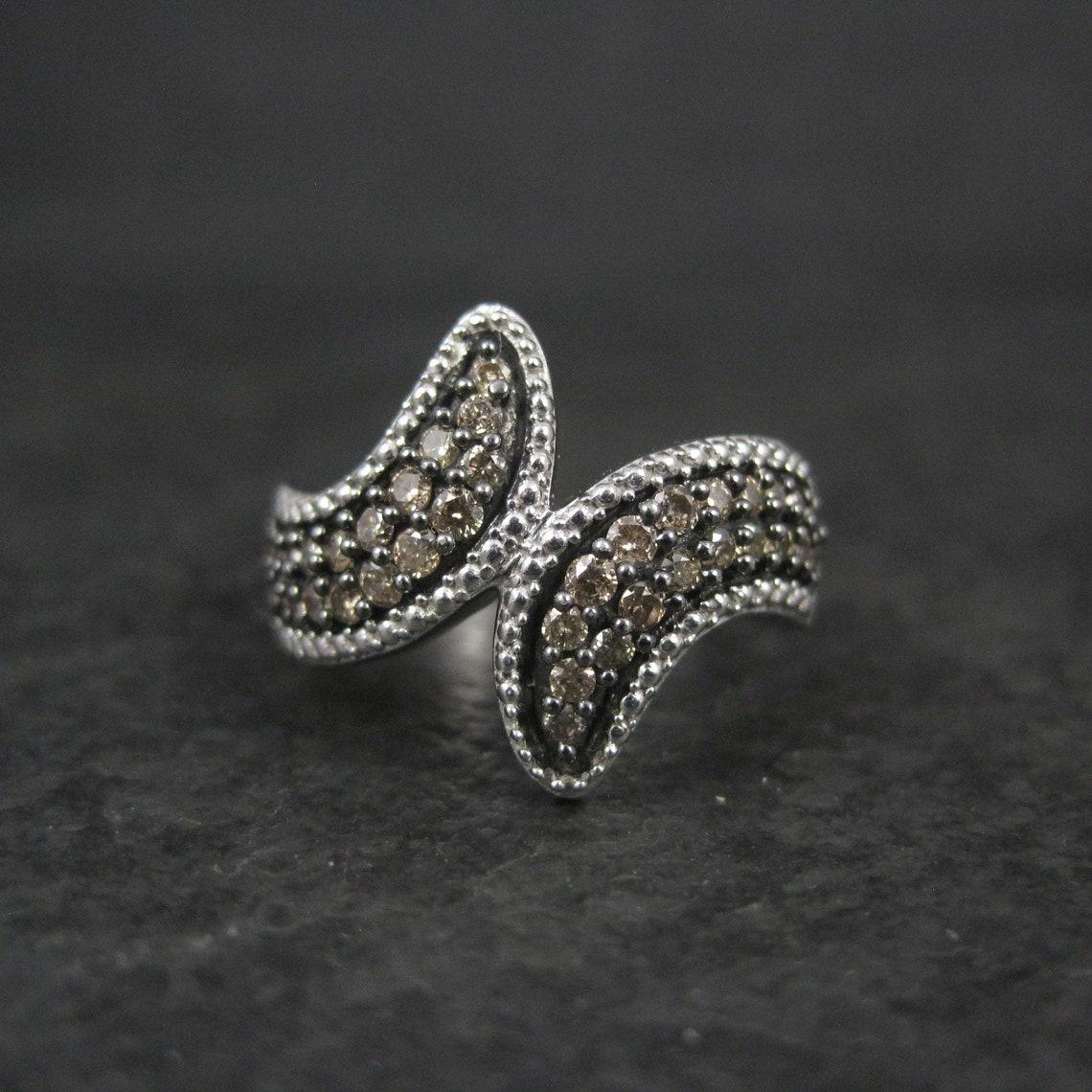 This beautiful estate ring is sterling silver.
It features 38 round cut .03 Carat champagne colored diamonds.
The face of this ring measures 5/8 of an inch north to south.
Size 5
Marks: 925, SJD
Condition: Excellent