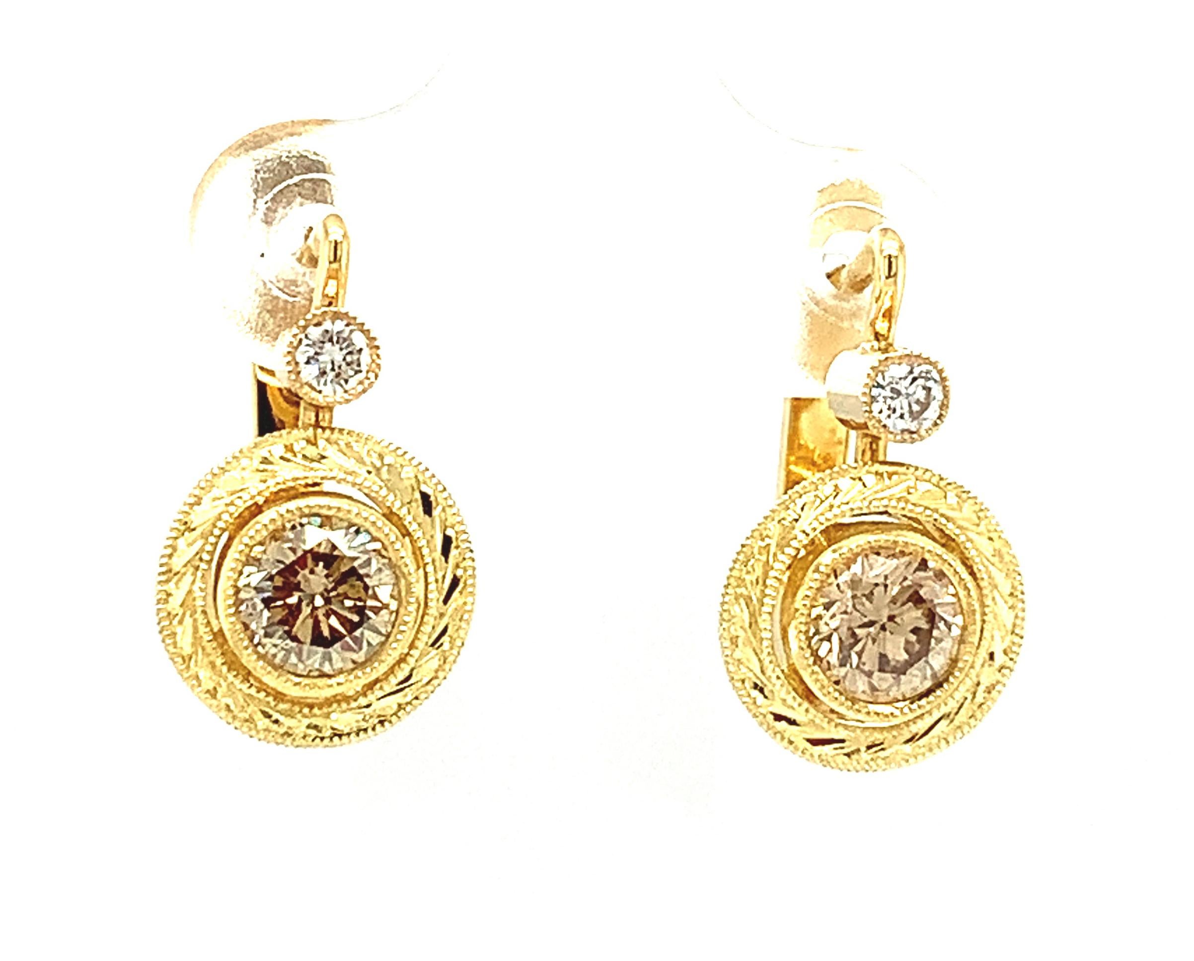 These elegant and stylish lever-back drop earrings feature exquisite, round brilliant cut champagne color diamonds and round white diamonds in hand engraved 18k yellow gold bezels. A 