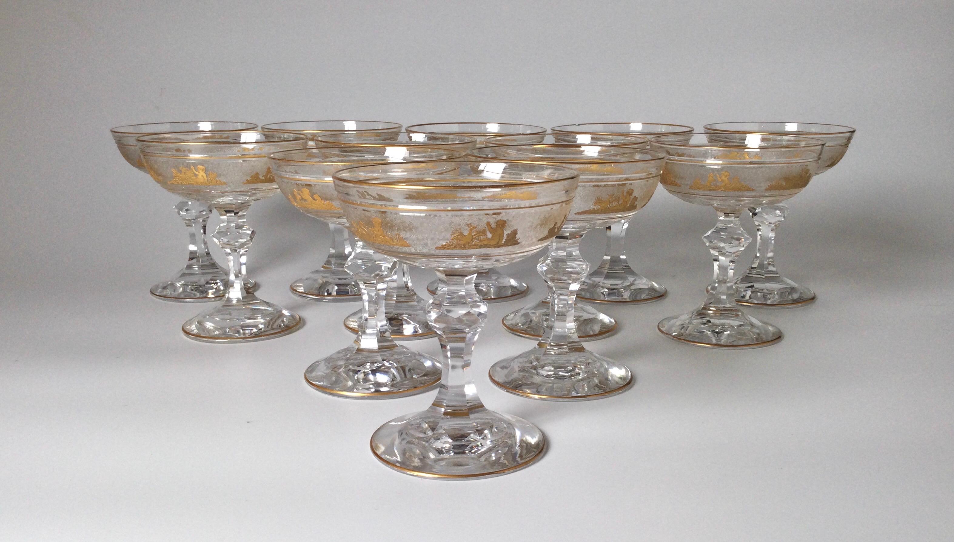    A magnificent set of 12 champagne glasses made by Val St. Lambert. Each one is handblown, panel cut bowl with cameo cut frieze of Roman figures embellished with gold leaf. This pattern is one of Val St. Lambert's finest and presents an opulent