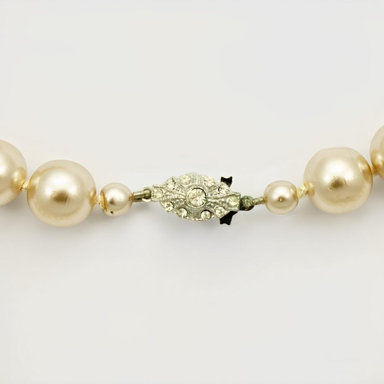Magnifique collier de perles de verre champagne avec un fermoir en argent serti de strass. Les perles lustrées sont nouées entre chaque perle. Longueur 81 cm / 31.8 pouces. Les perles mesurent 12 mm. Le collier est en très bon état, avec peu d'usure