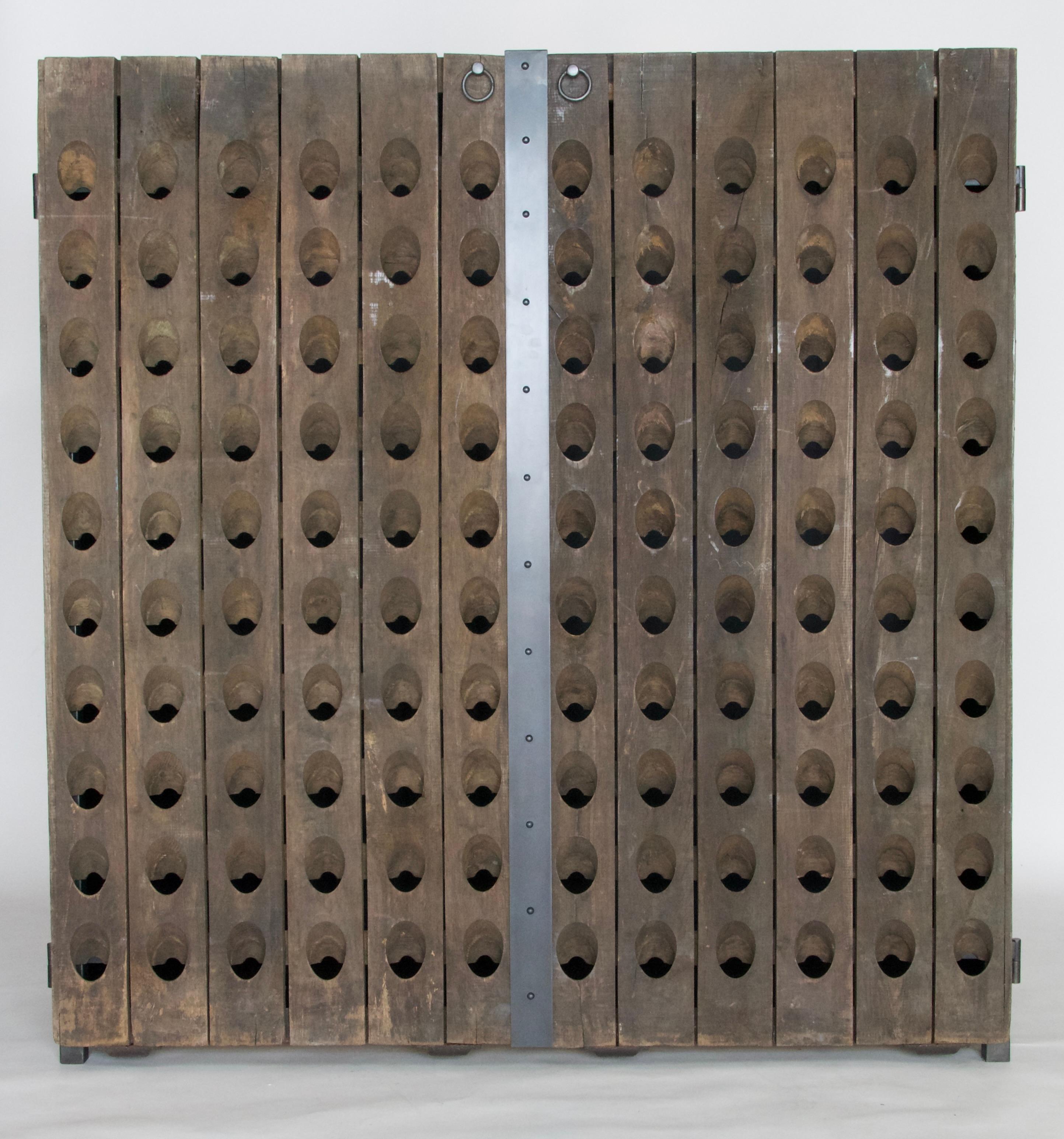This distinctive cabinet integrates an authentic 1940s French champagne rack, repurposing its front panels into striking doors. Mounted onto a steel frame with a gunmetal patina, the piece exudes a bold yet refined character. Inside, three