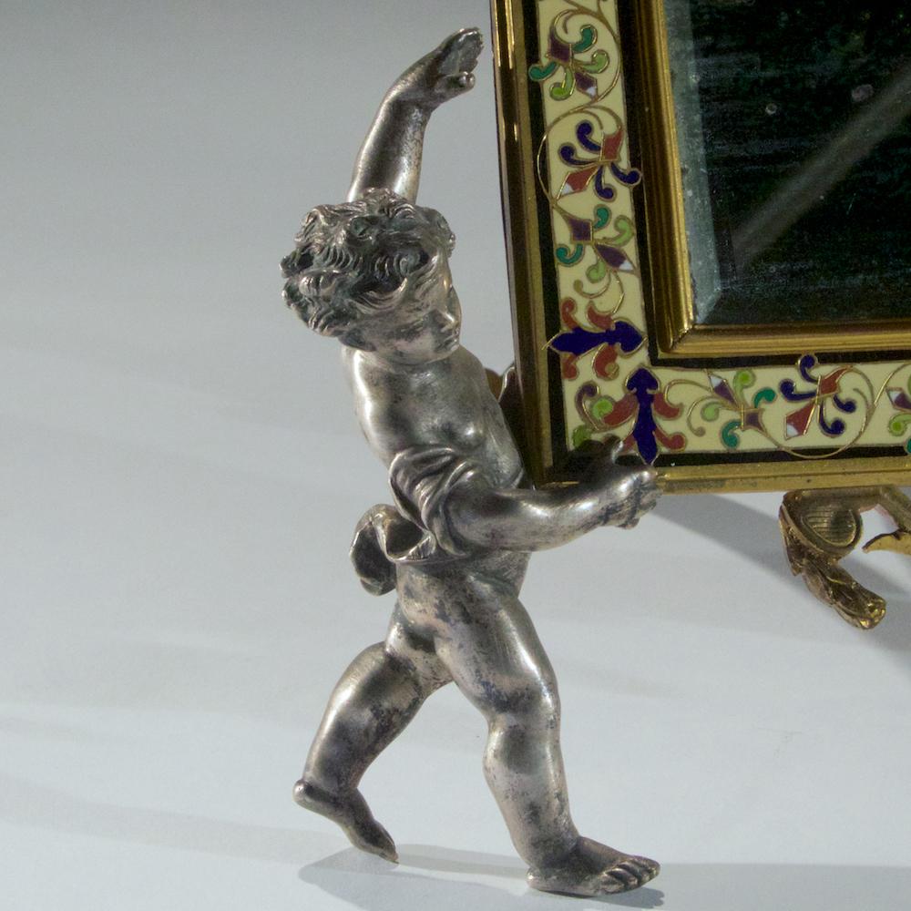 Fine Champlevé enamel and gilt bronze vanity mirror held by cherubs. The beveled mirror supported by silvered-bronze cherubs.

Date: 19th century
Origin: French
Dimension: 13 x 10 3/4 inches.